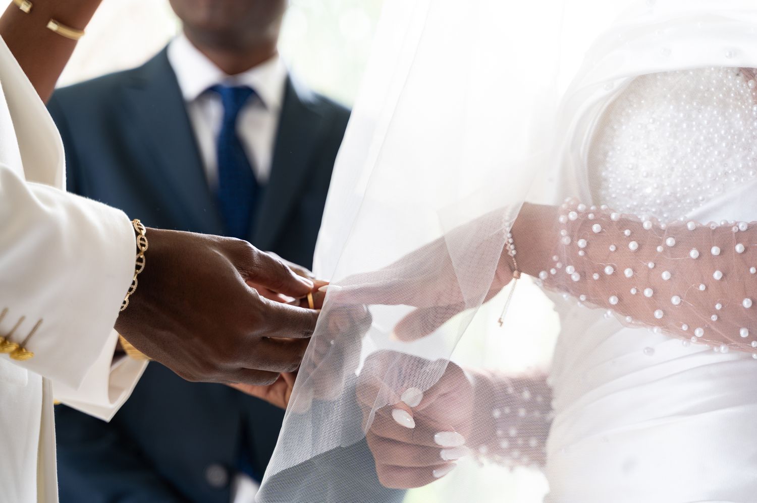 Close-up of groom placing wedding ring on brides hand during ring exchange ceremony.