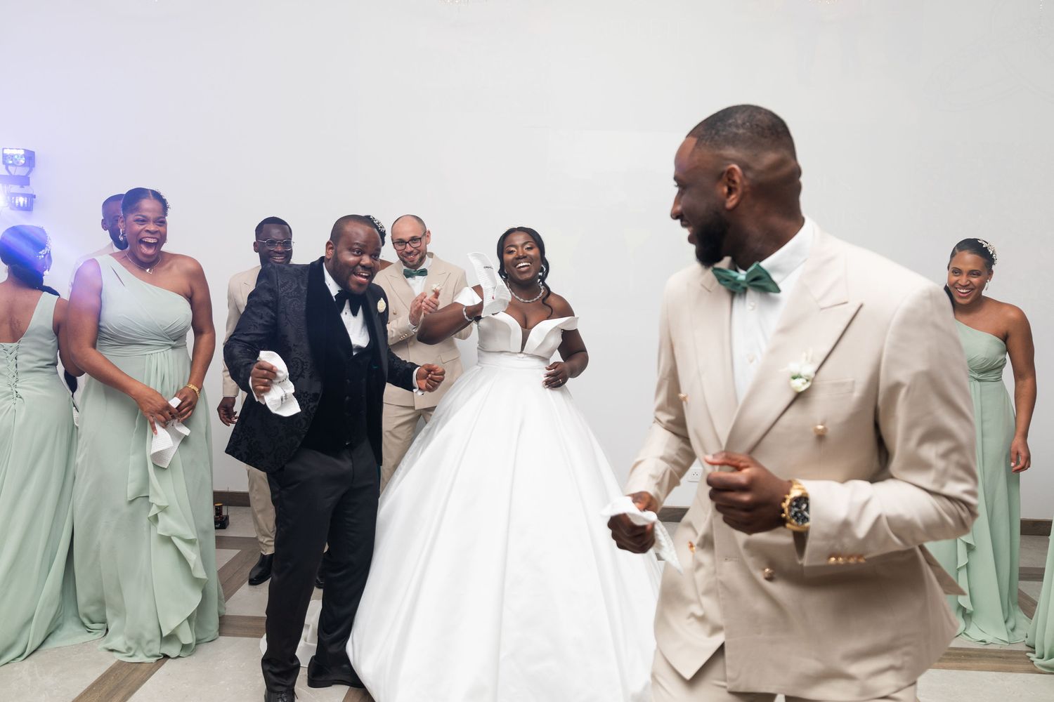 Wedding reception entrance with bride in ballgown and groom in beige suit with guests.