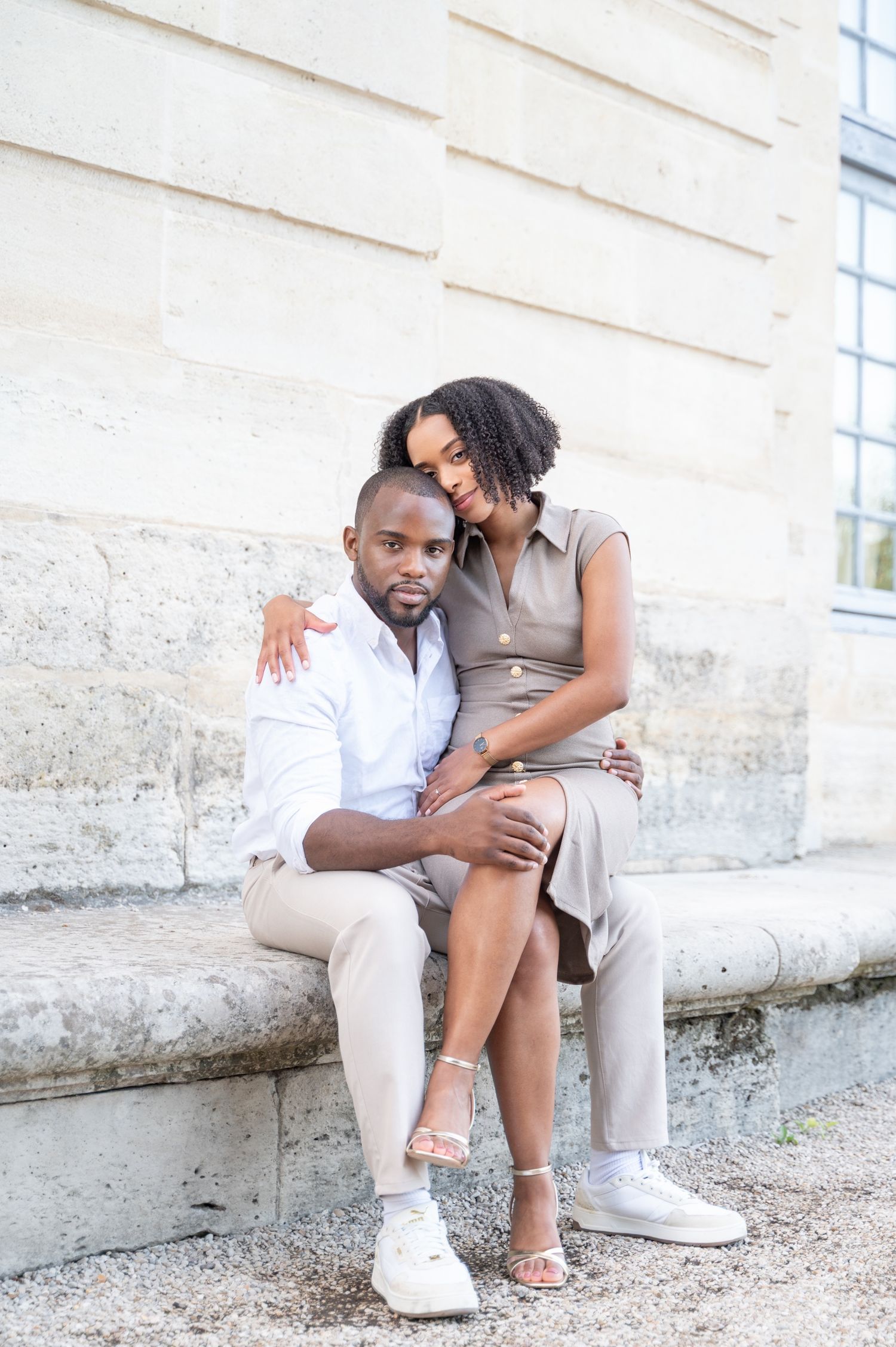 Couple sitting intimately on stone steps, woman resting head on mans shoulder.