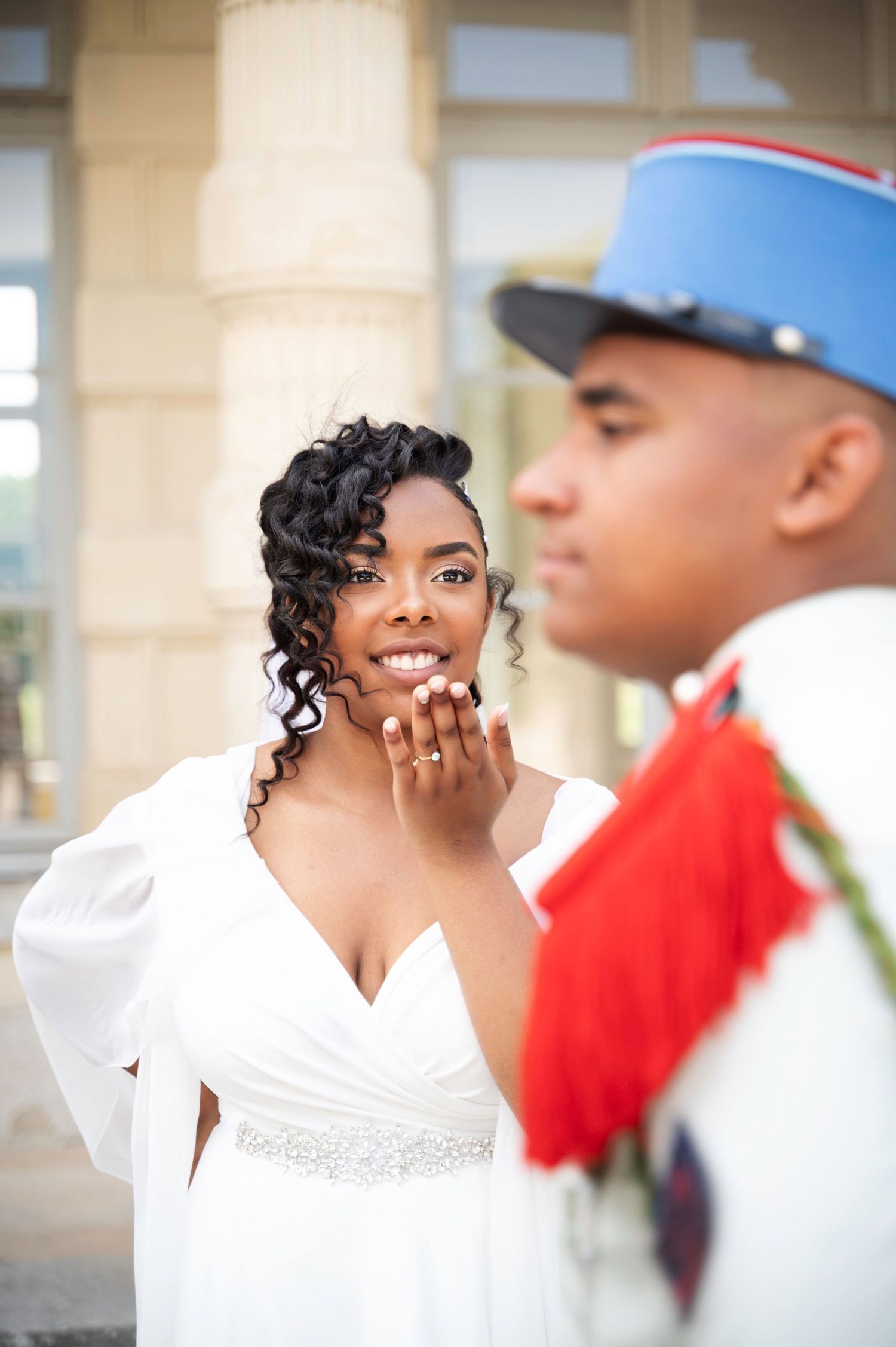 Radiant Black bride in white gown blows a kiss to her military uniformed groom.