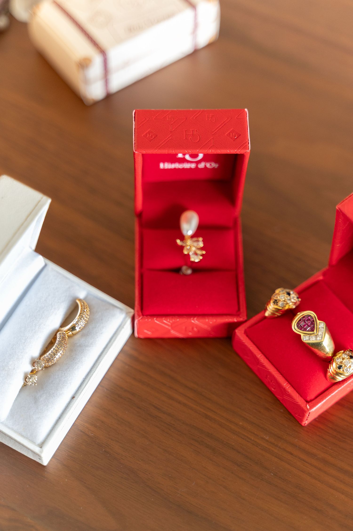 Gold rings displayed in red jewelry boxes on wooden table for wedding.