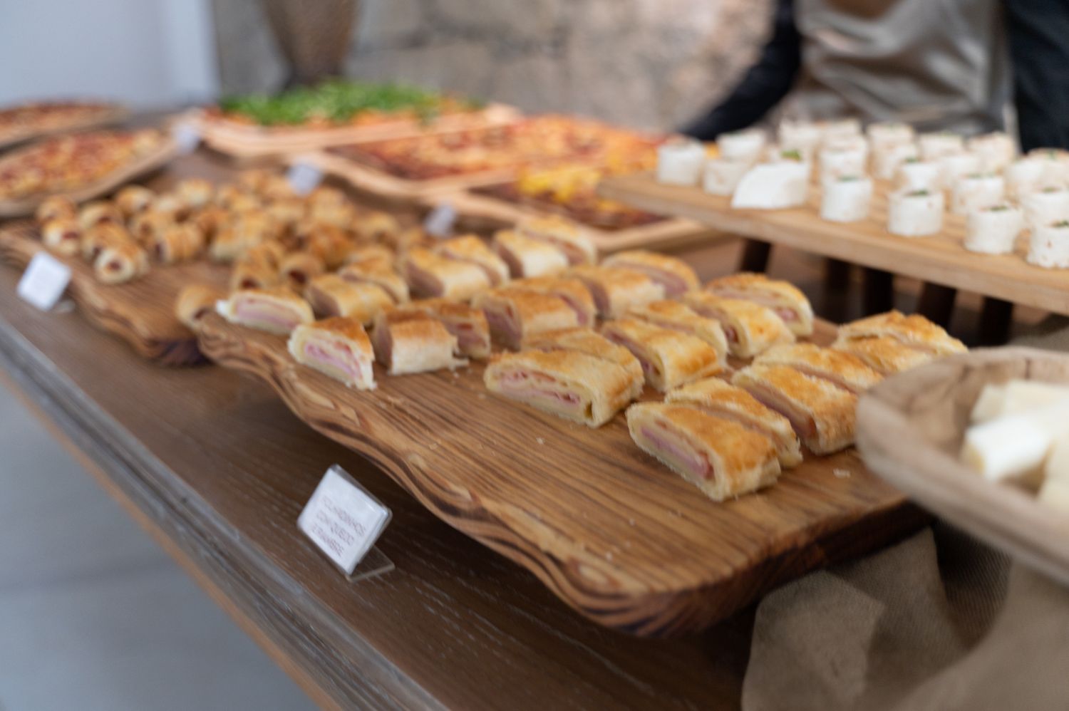 Elegant wedding reception buffet with assorted pastries and finger foods on wooden boards.