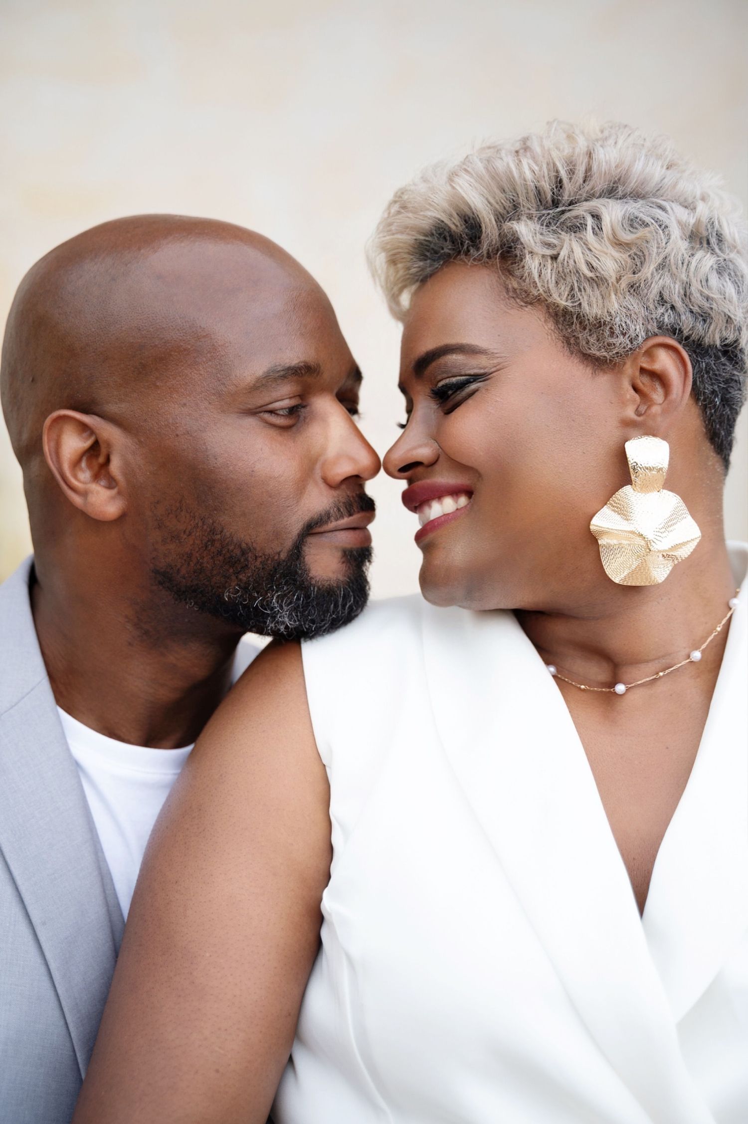 Romantic couple nearly kissing, woman with short gray hair wearing gold earrings.