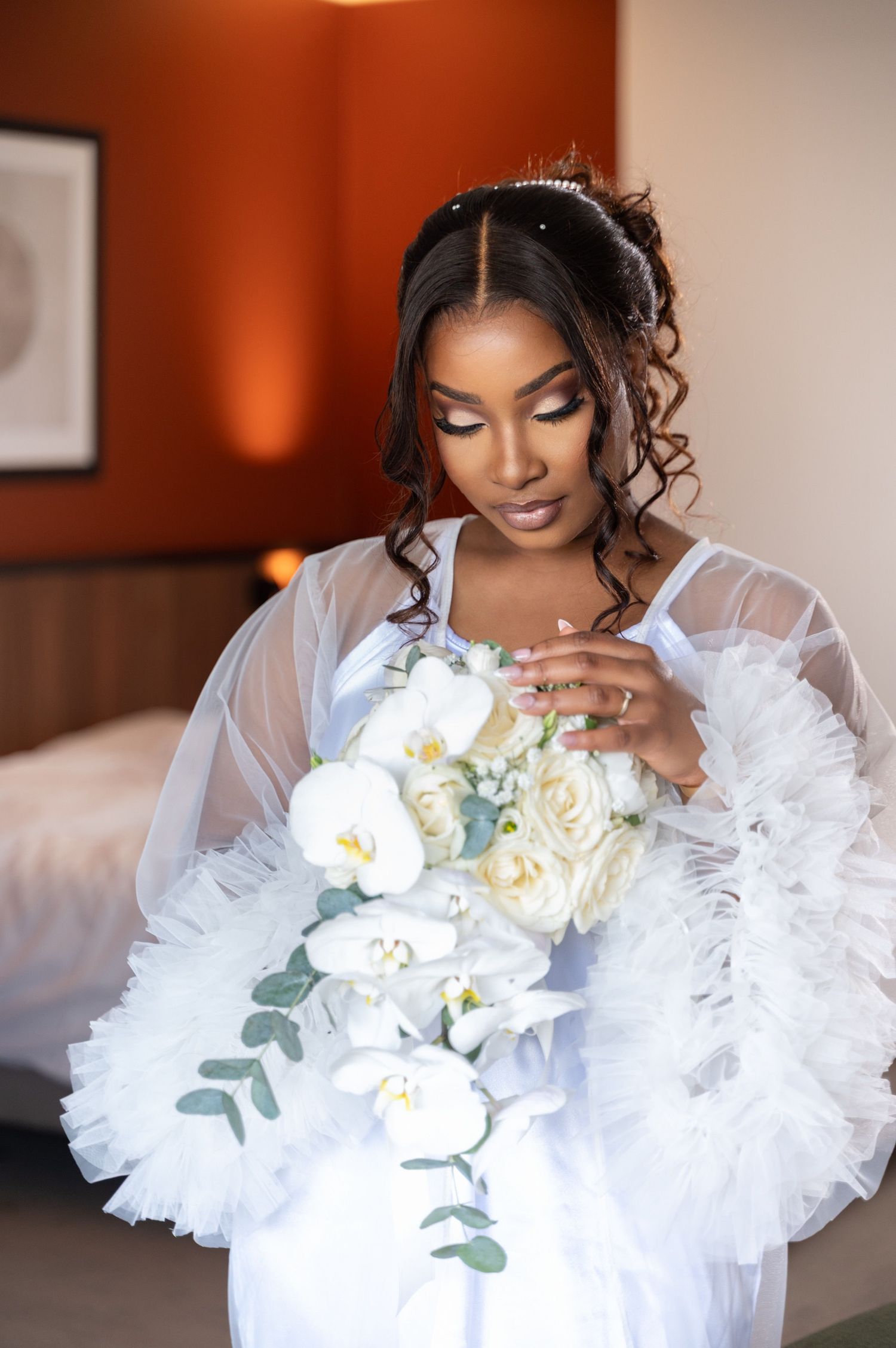 Beautiful Black bride in white robe holding cascading white floral bouquet.