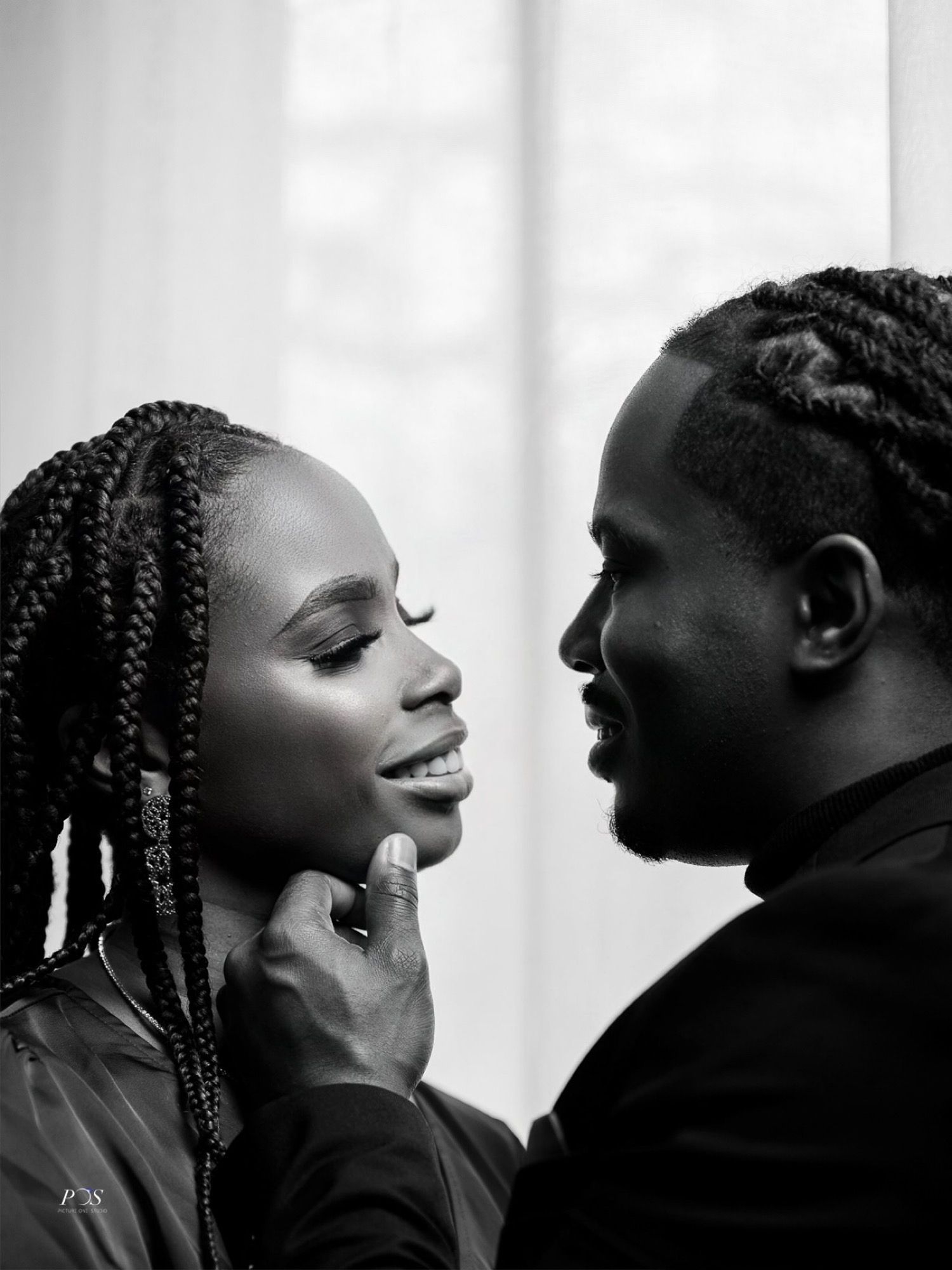 Intimate black and white portrait of couple sharing tender moment with man cradling womans face.