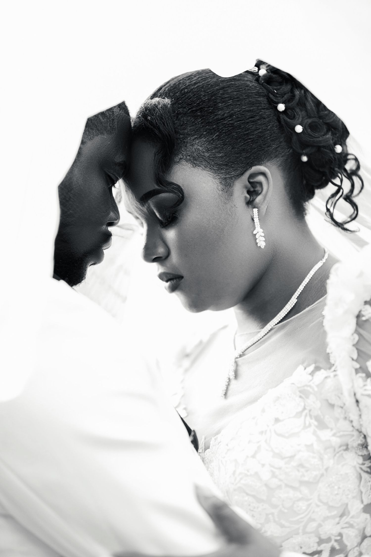 Intimate black and white portrait of bride and groom touching foreheads, bride wearing lace gown.