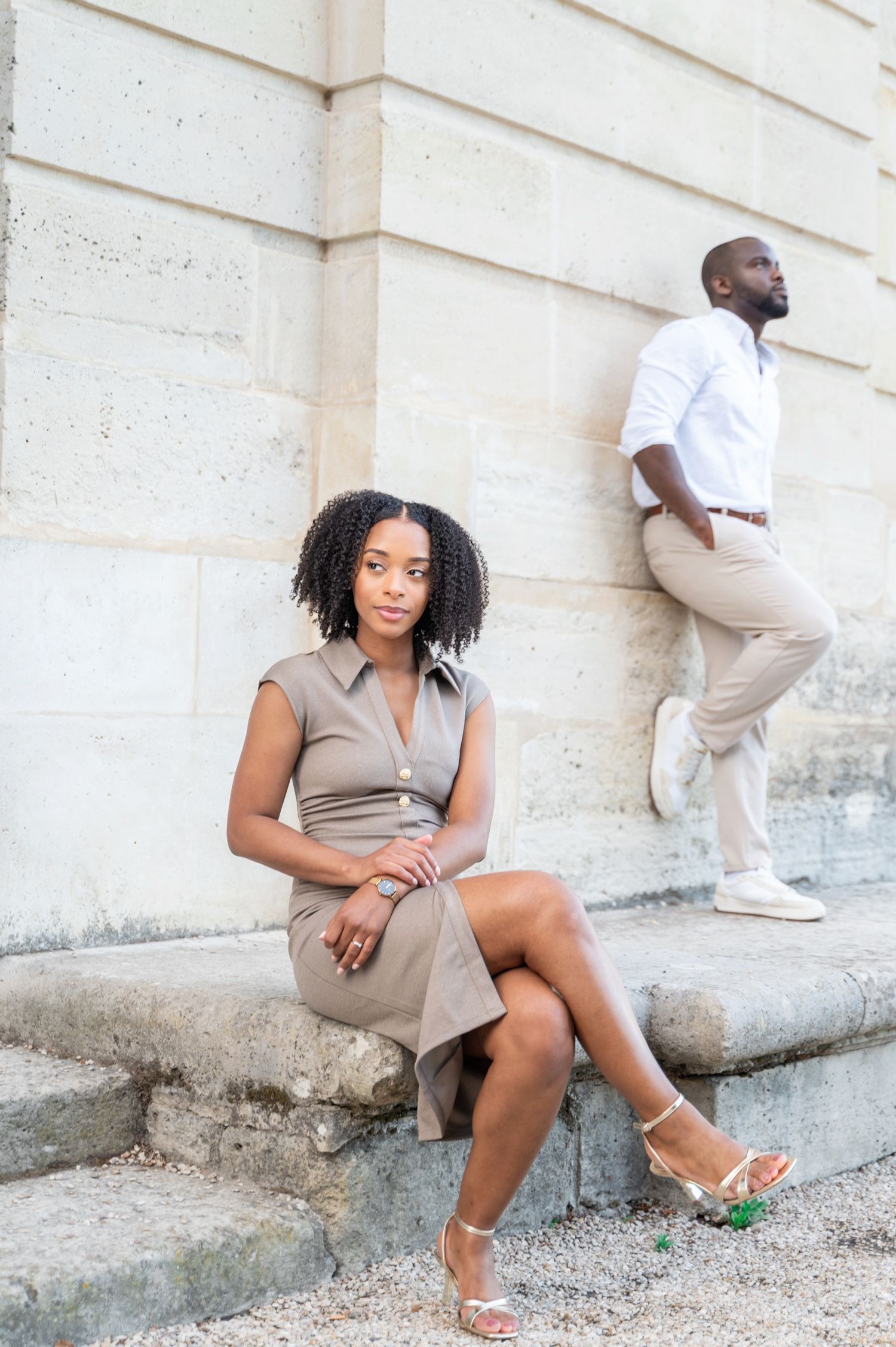 Elegant couple posing on stone steps against a classic limestone building exterior.