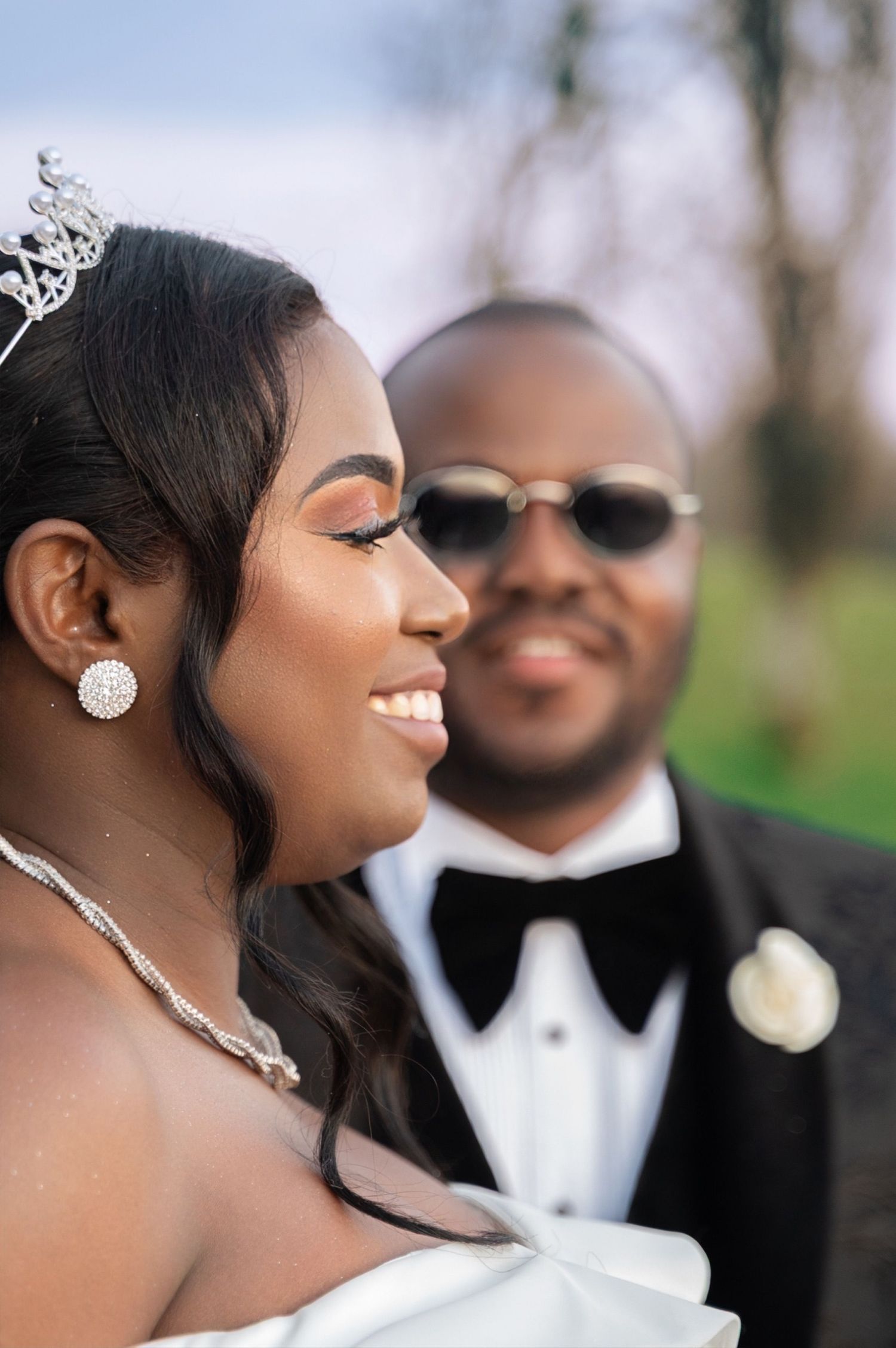 Beautiful Black bride wearing tiara and diamond earrings with groom in tuxedo.