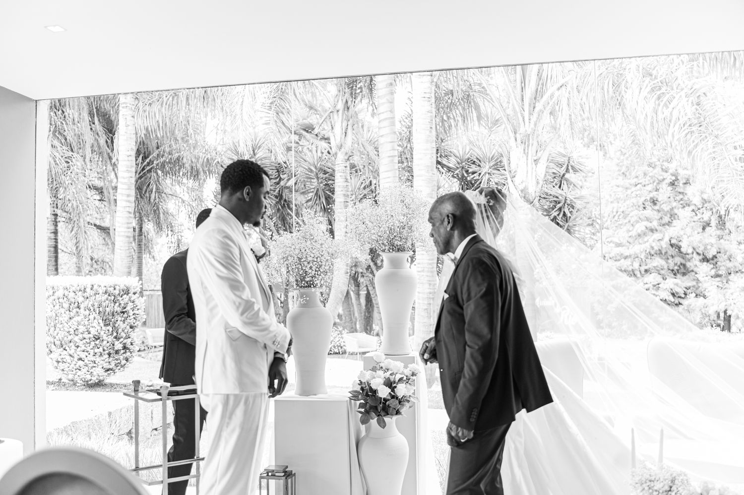 Black and white photo of a bride and groom at the wedding altar with a officiant during their ceremony.