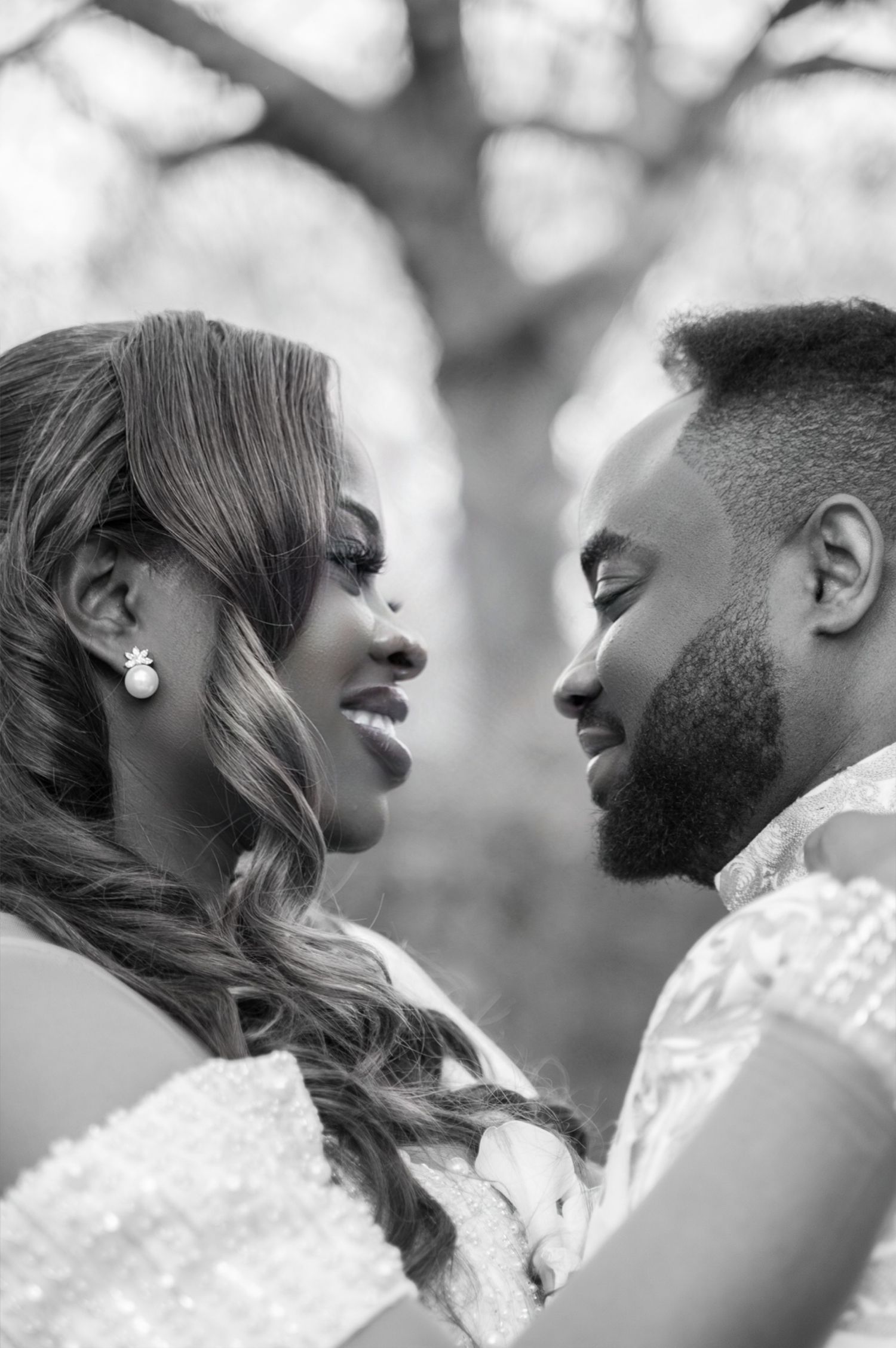 Black and white close-up of an engaged couple gazing lovingly at each other outdoors.