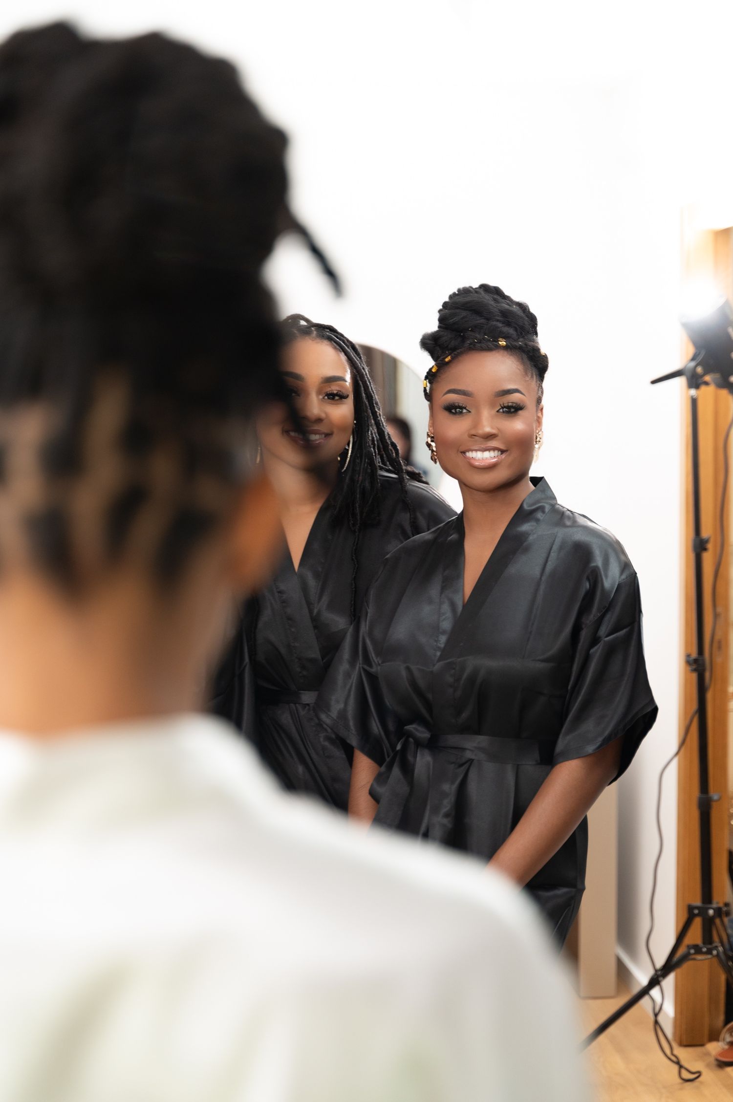 Smiling bridesmaid in black satin robe poses during bridal party getting-ready session.