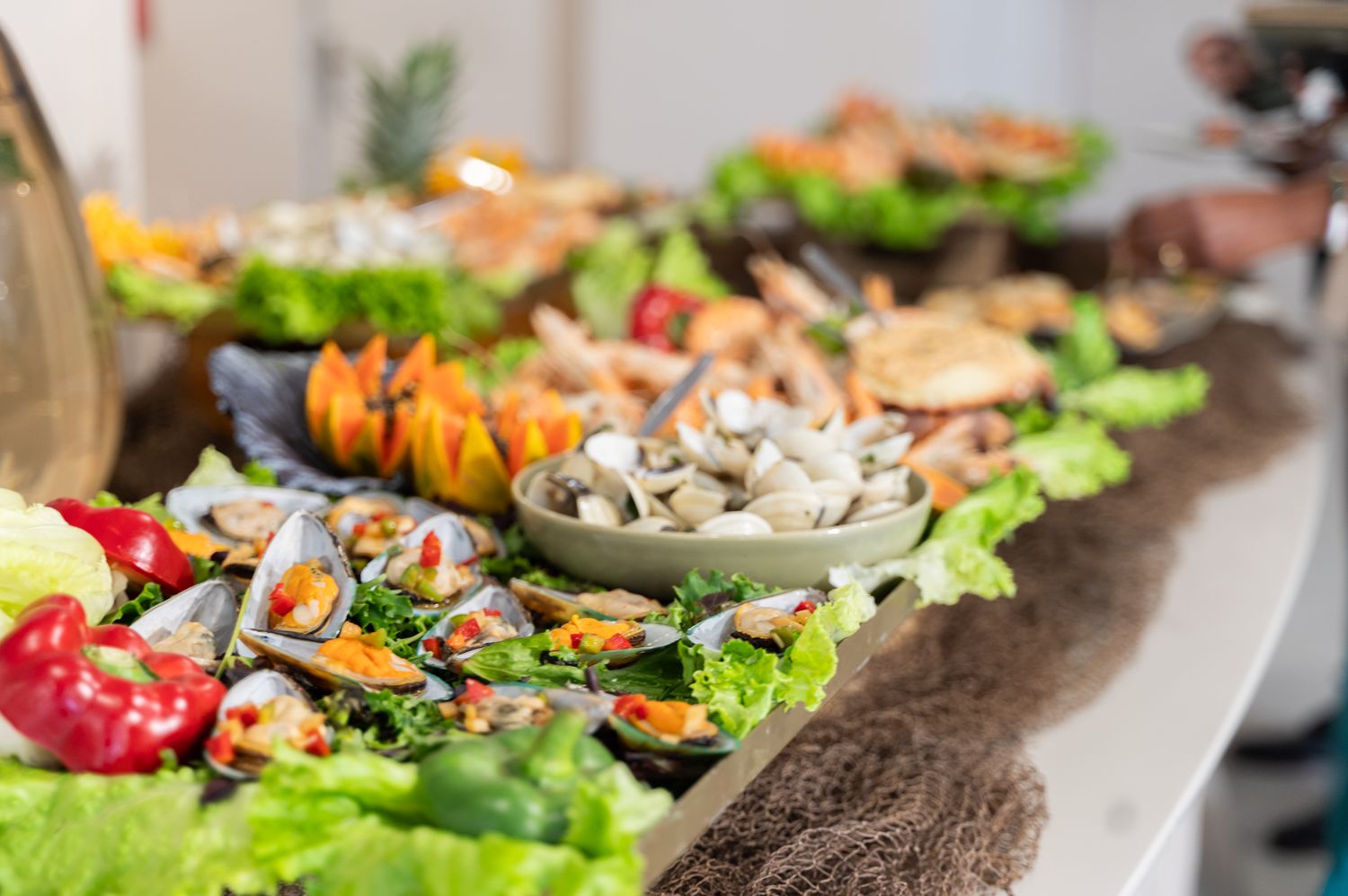 Elegant seafood buffet display with mussels, clams, and fresh vegetables on decorative lettuce-lined serving dishes.