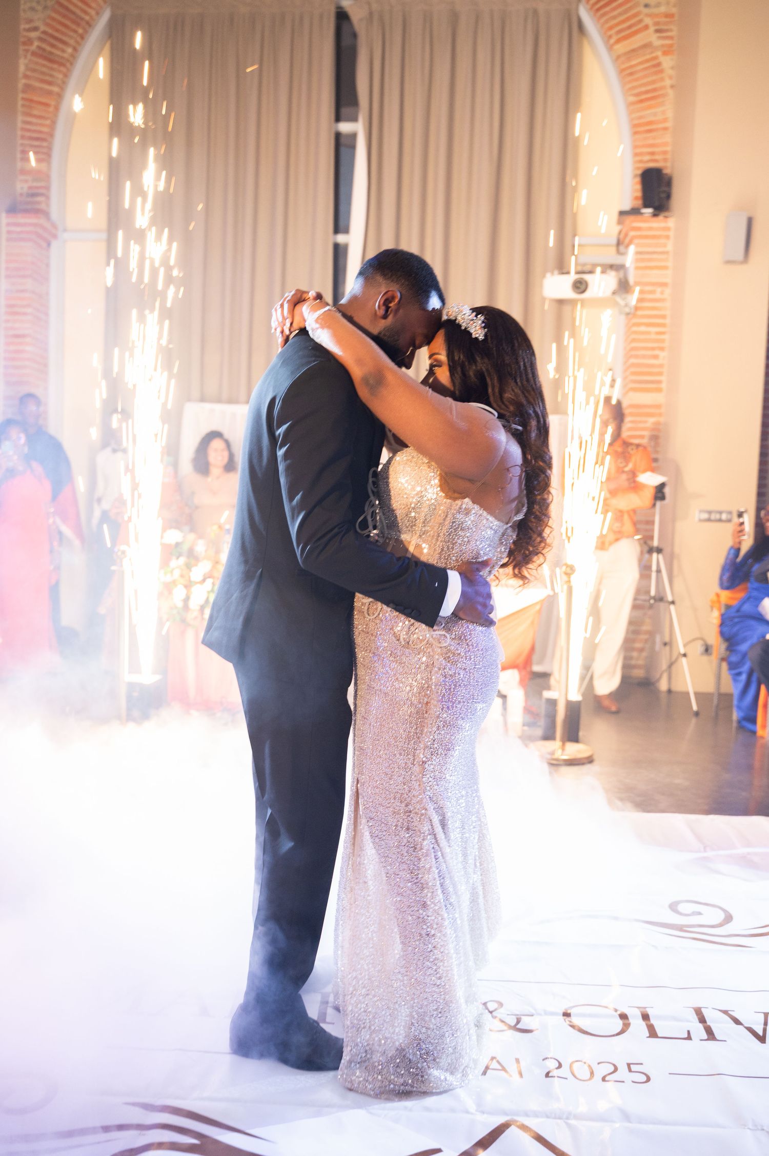 Bride in sequin mermaid gown and groom share a passionate kiss amid cold sparkler fountains and swirling fog.