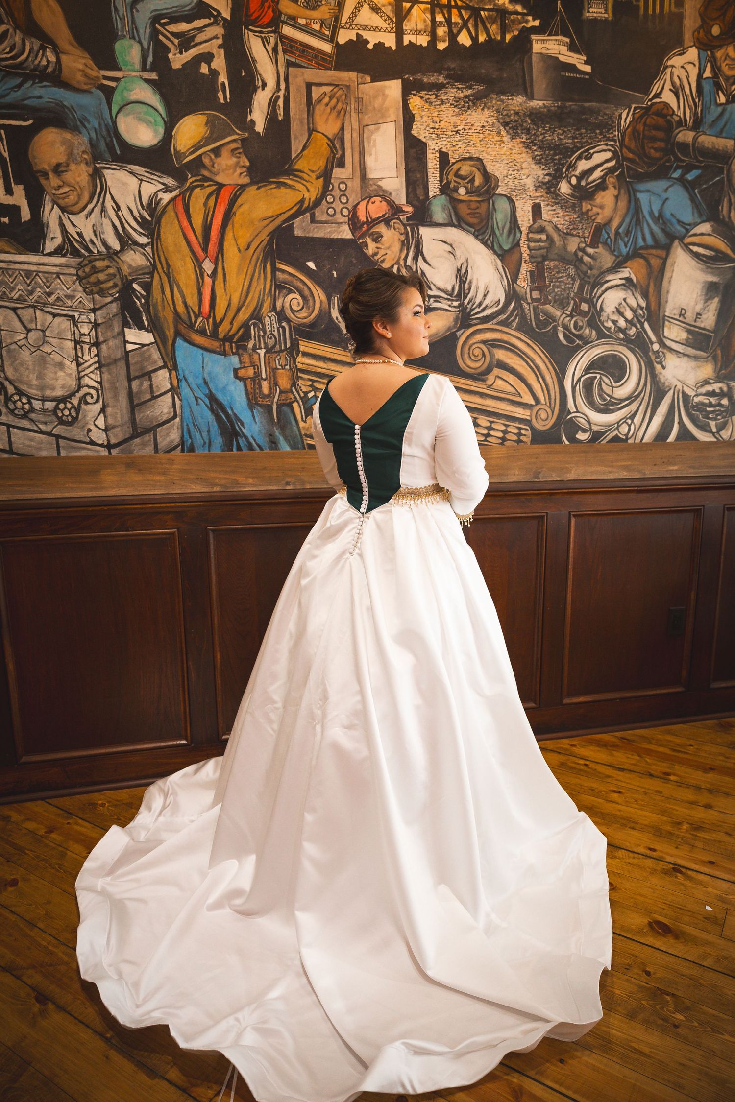 White wedding gown with flowing train photographed against vintage mural background.
