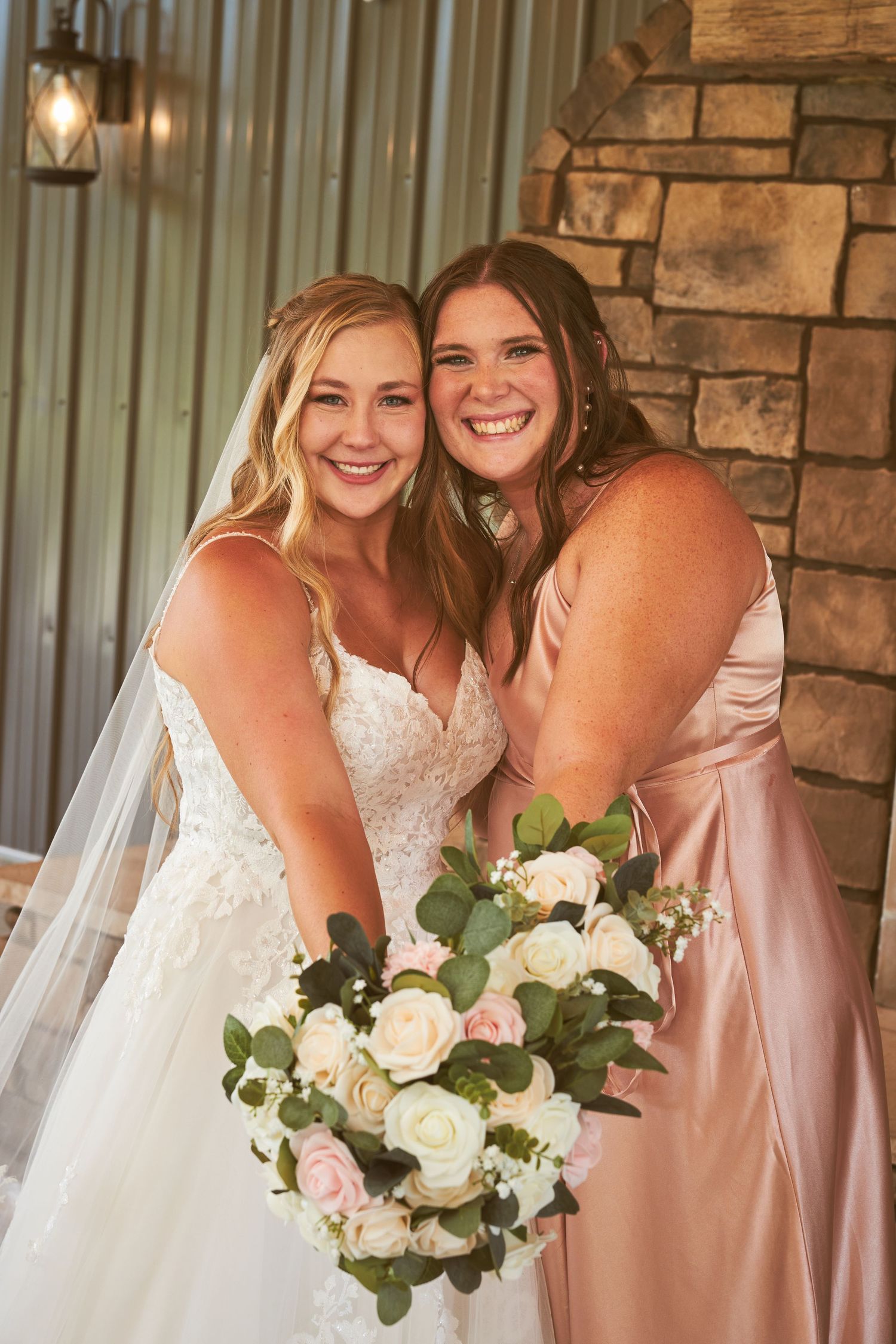 Wedding party holding bouquets of white roses against stone wall backdrop.