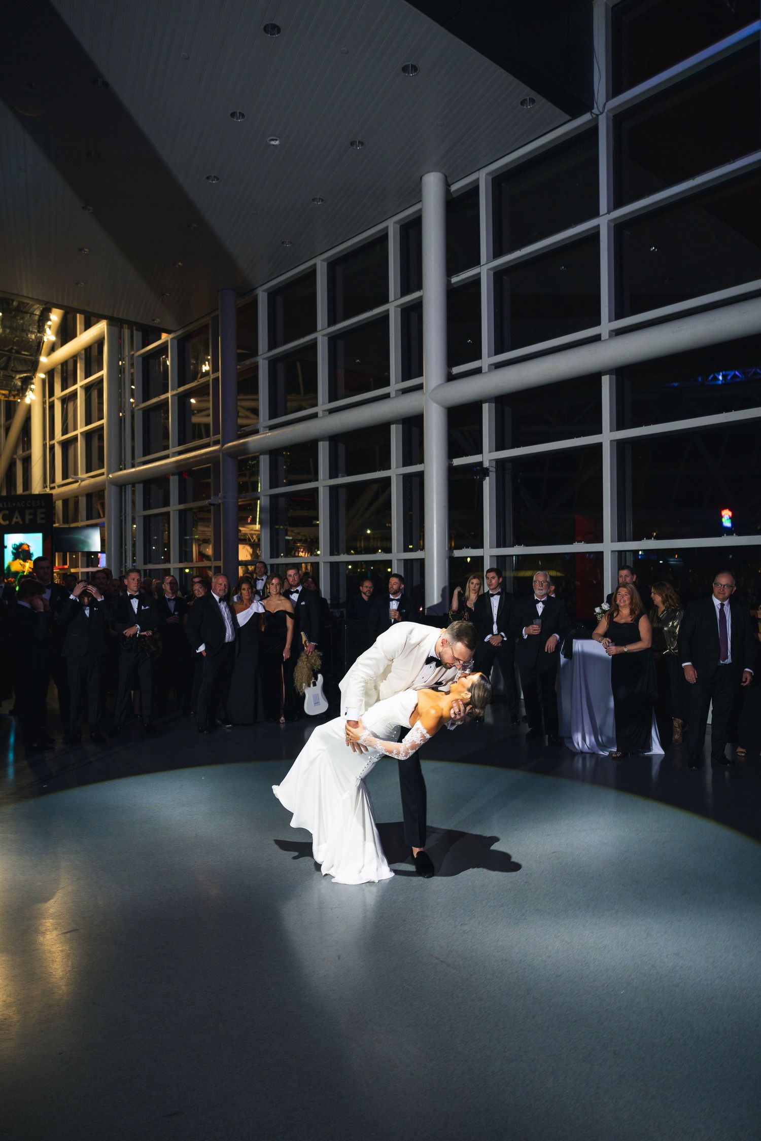 A couple performs an intimate dip during their wedding dance as guests watch from the sidelines.