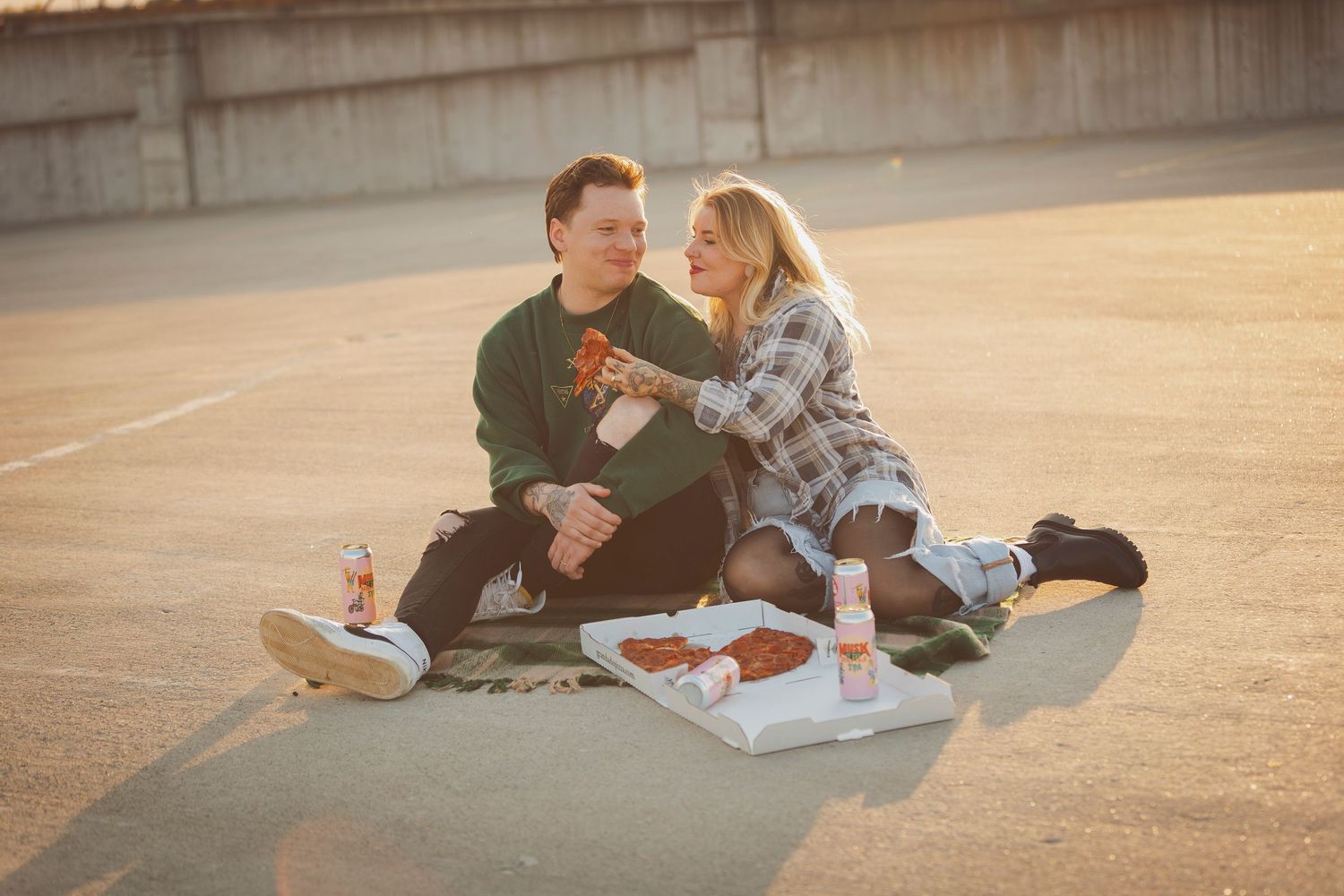 Casual outdoor picnic scene with couple relaxing during sunset on urban ground.