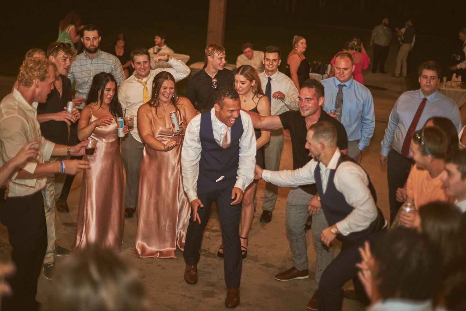 Wedding guests gather on the dance floor for an energetic group dance moment.
