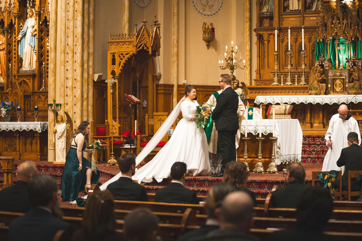 Traditional church wedding ceremony in ornate cathedral with golden details and wooden pews.
