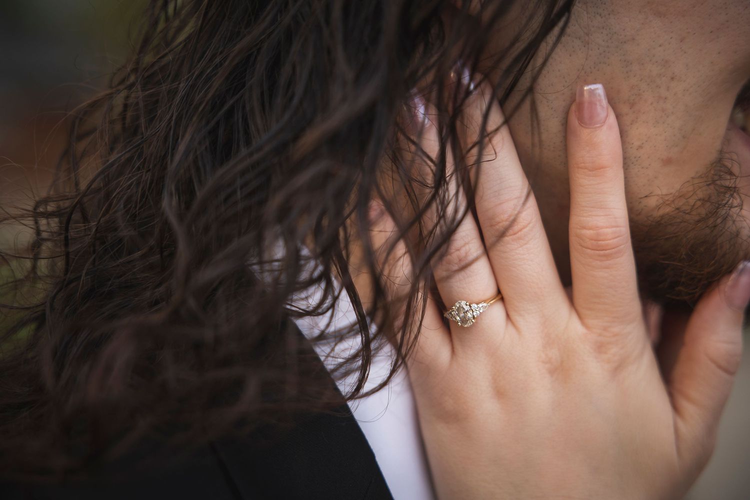 Close-up shot of hands showing an engagement ring with natural lighting.