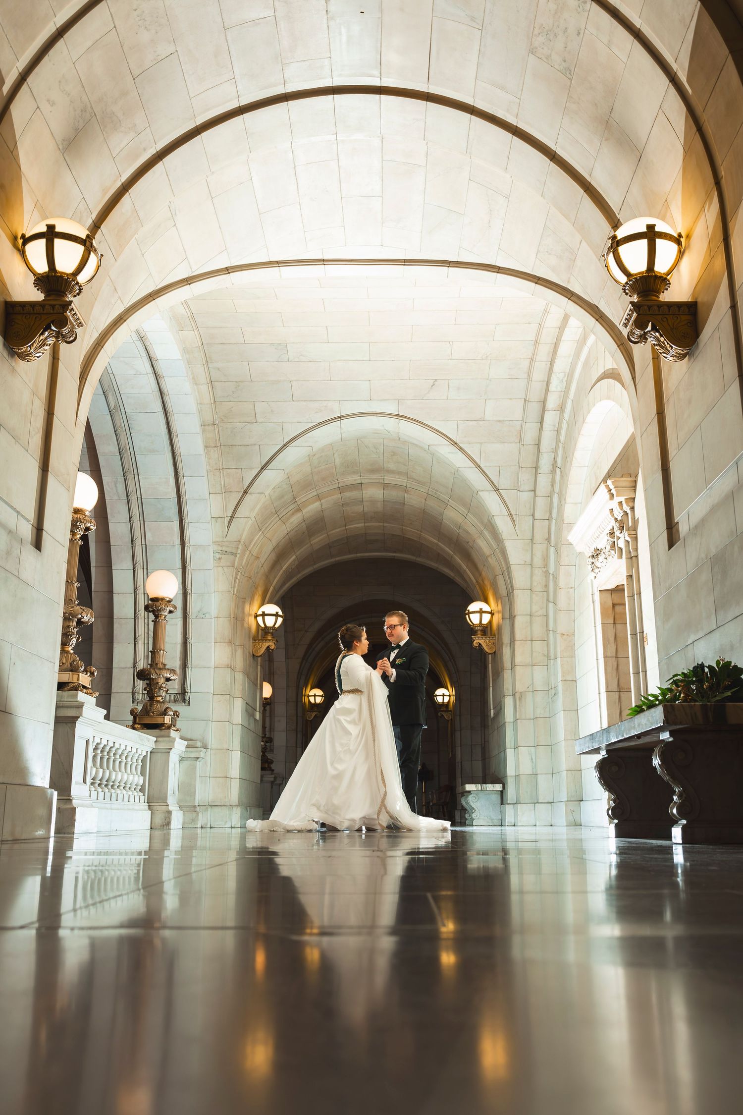 Wide angle shots of a bridal couple in an elegant stone hallway with vaulted ceilings.
