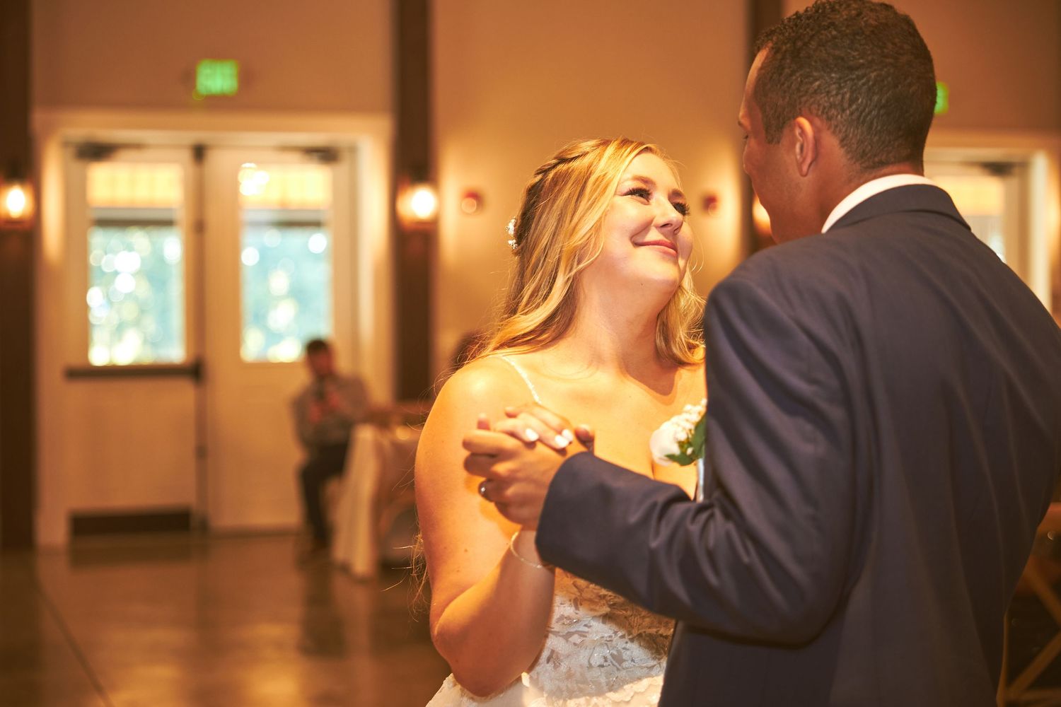 Romantic first dance moment captured in warmly lit reception venue.