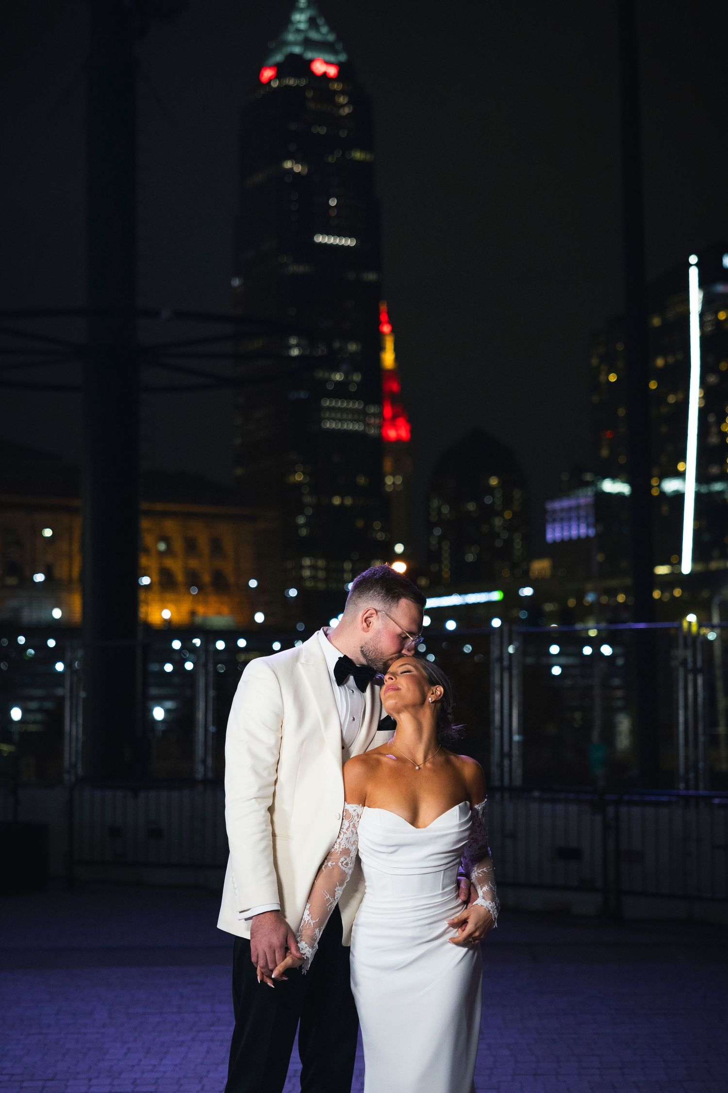 An intimate moment captured against a dramatic cityscape with twinkling lights.
