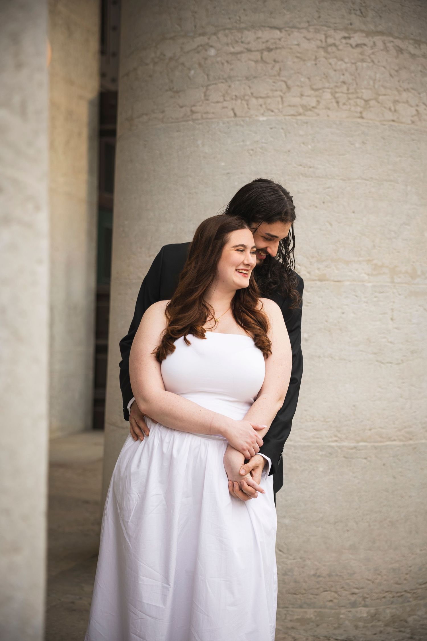 Couple sharing loving embraces during their photoshoot in a columned hallway.