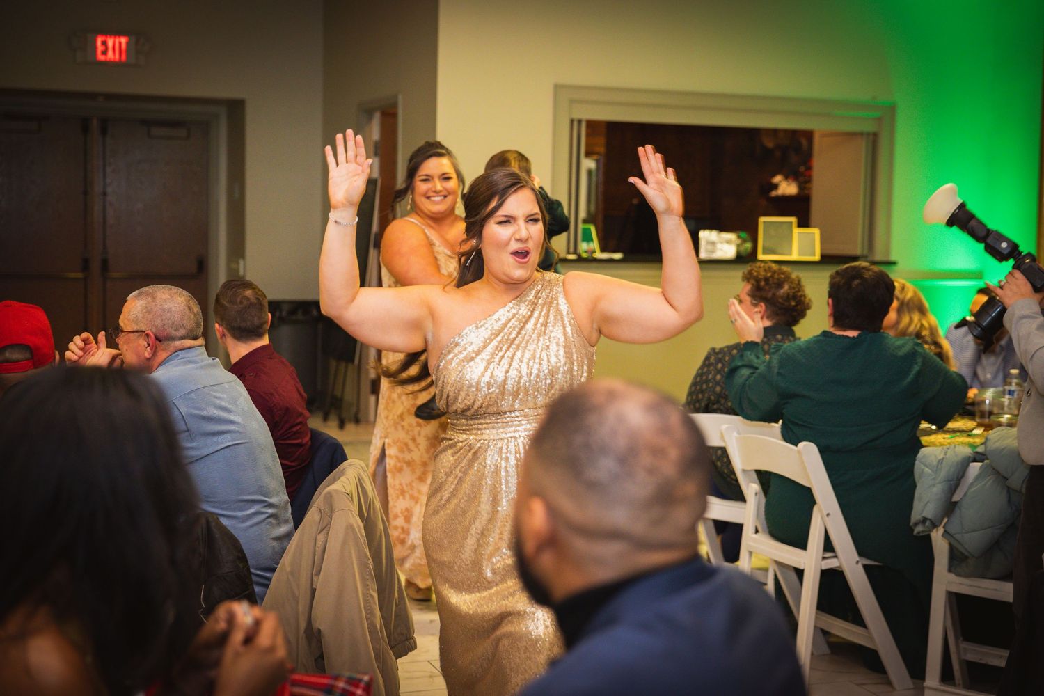 Event space decorated with white chairs and green uplighting creating an elegant atmosphere.
