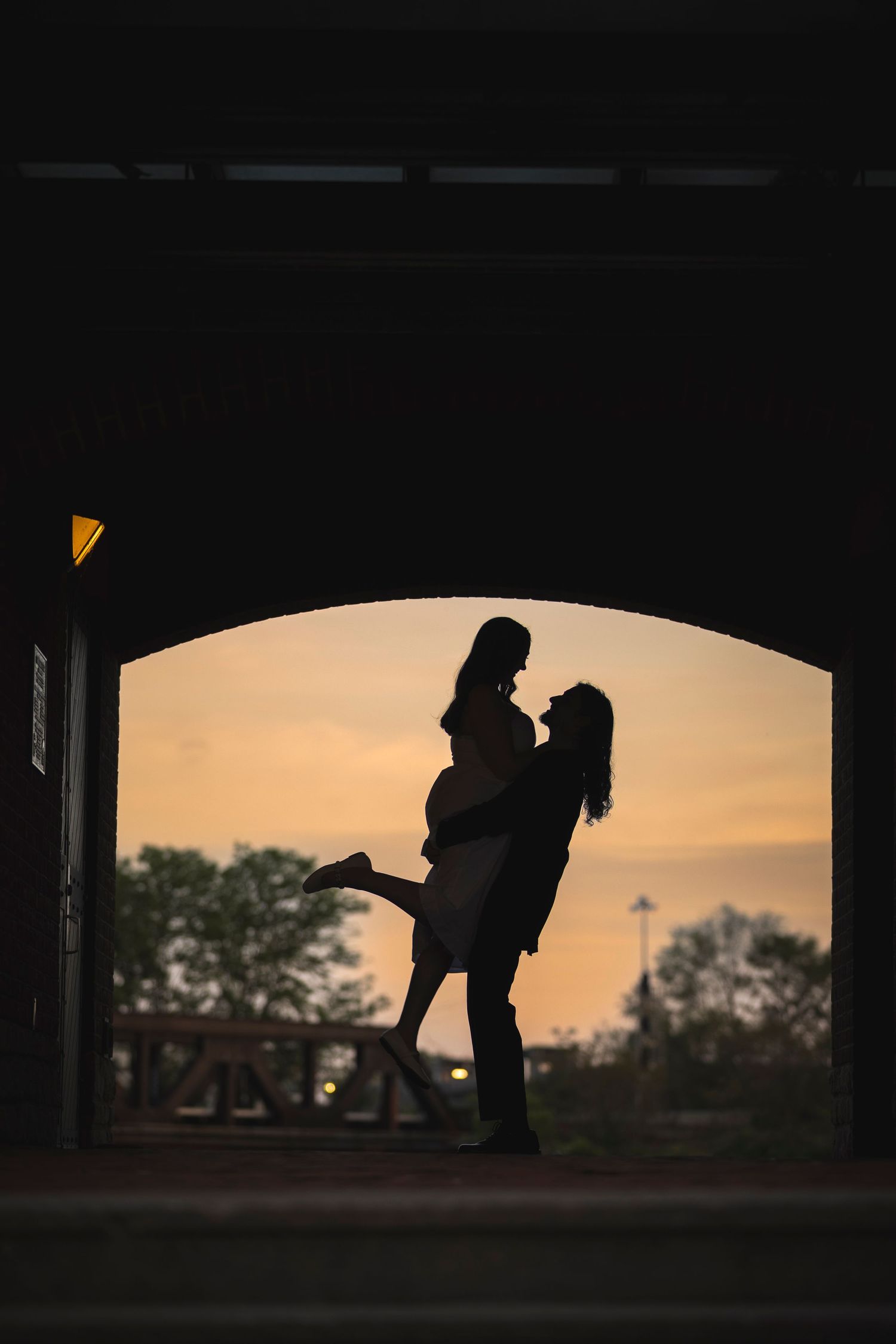 Romantic silhouettes framed within an archway during golden hour sunset.