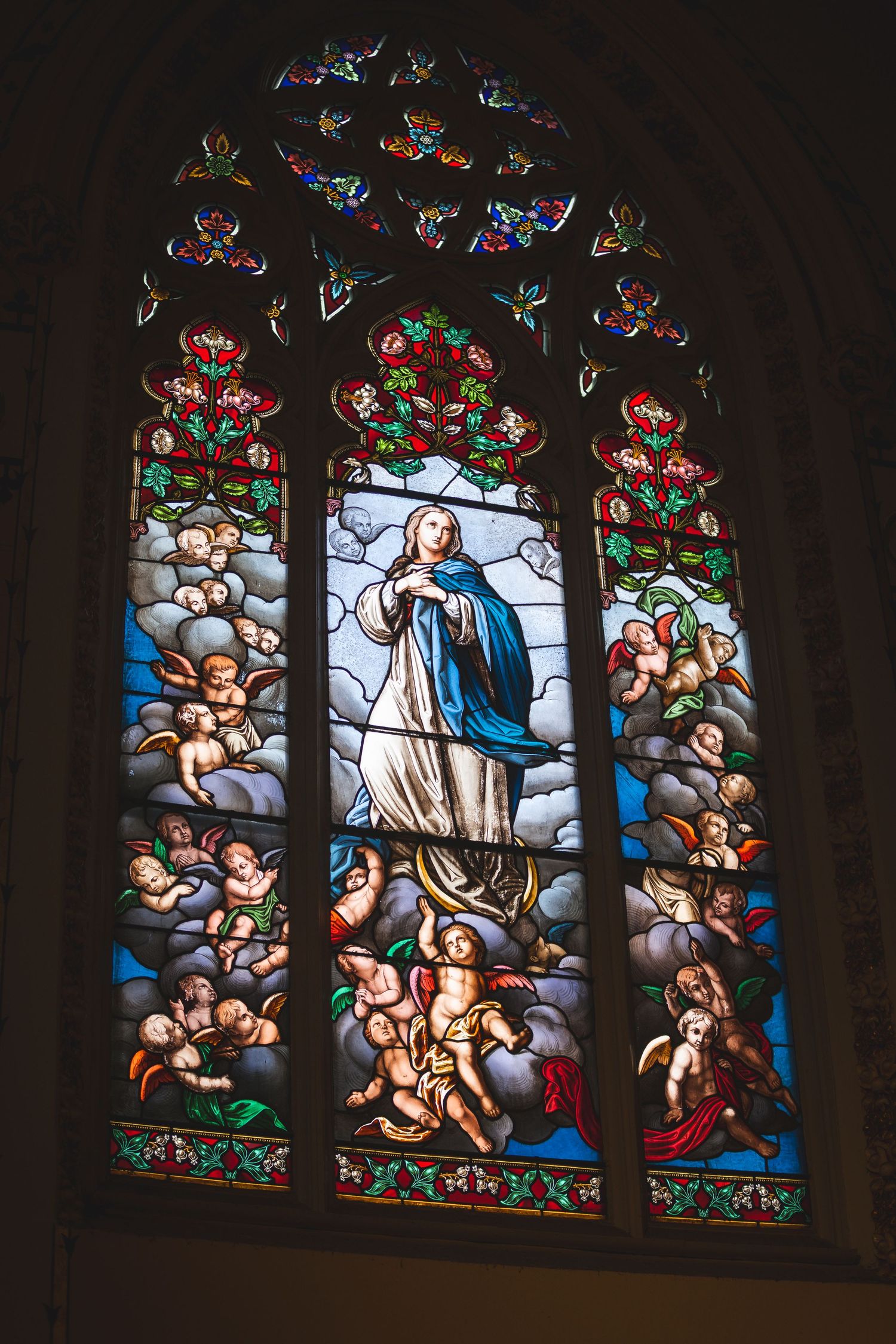 Colorful stained glass church window depicting religious scenes with ornate details.