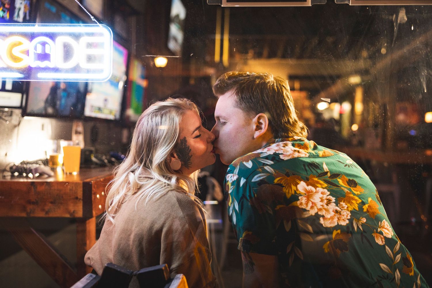 Bar interior with warm lighting and couple in casual attire.
