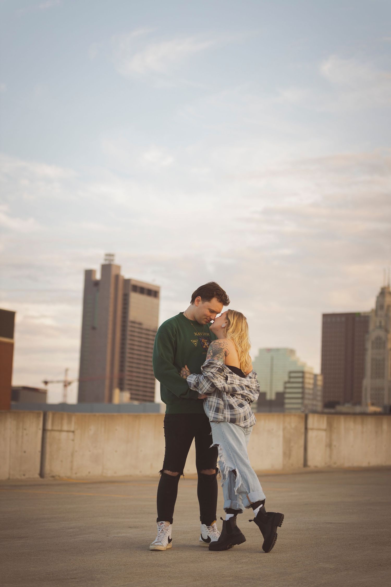 Couple dances on urban rooftop with city skyline in background.
