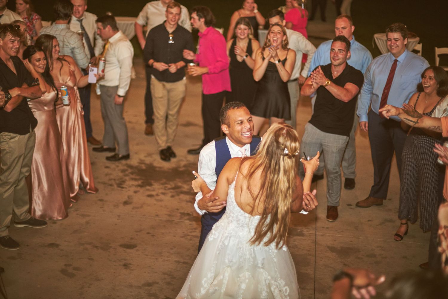 Newlyweds share a romantic dance moment surrounded by guests at their reception.
