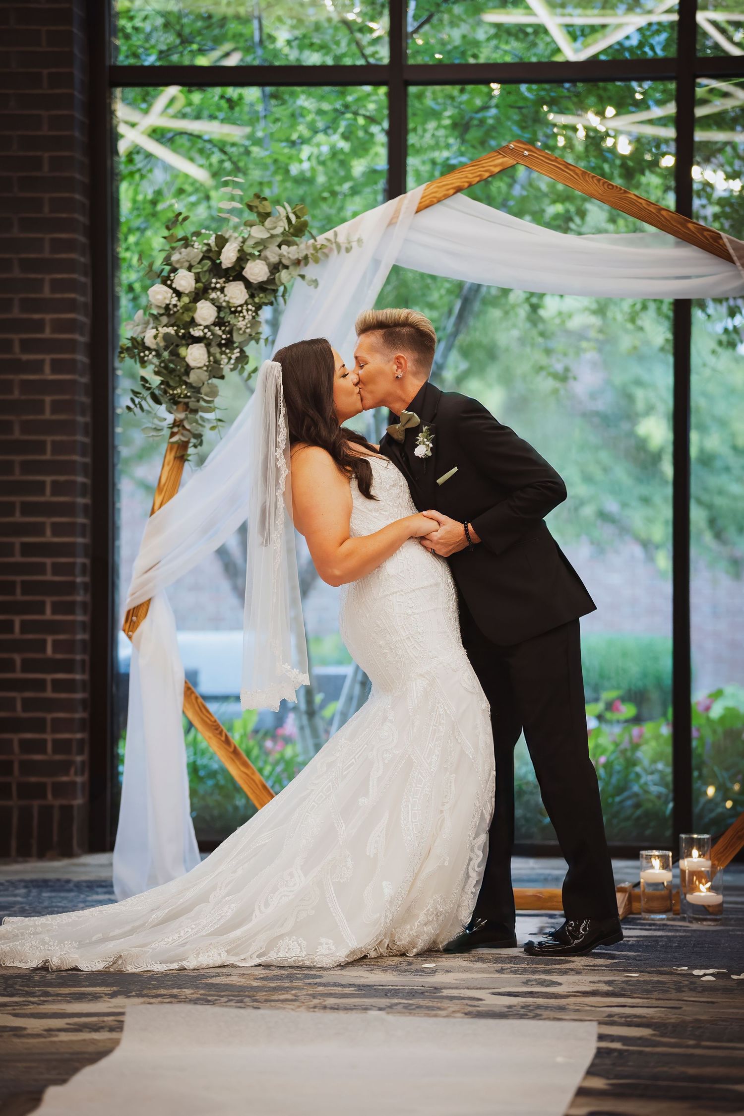 Romantic wedding moment under a decorated pavilion with white floral arrangements.