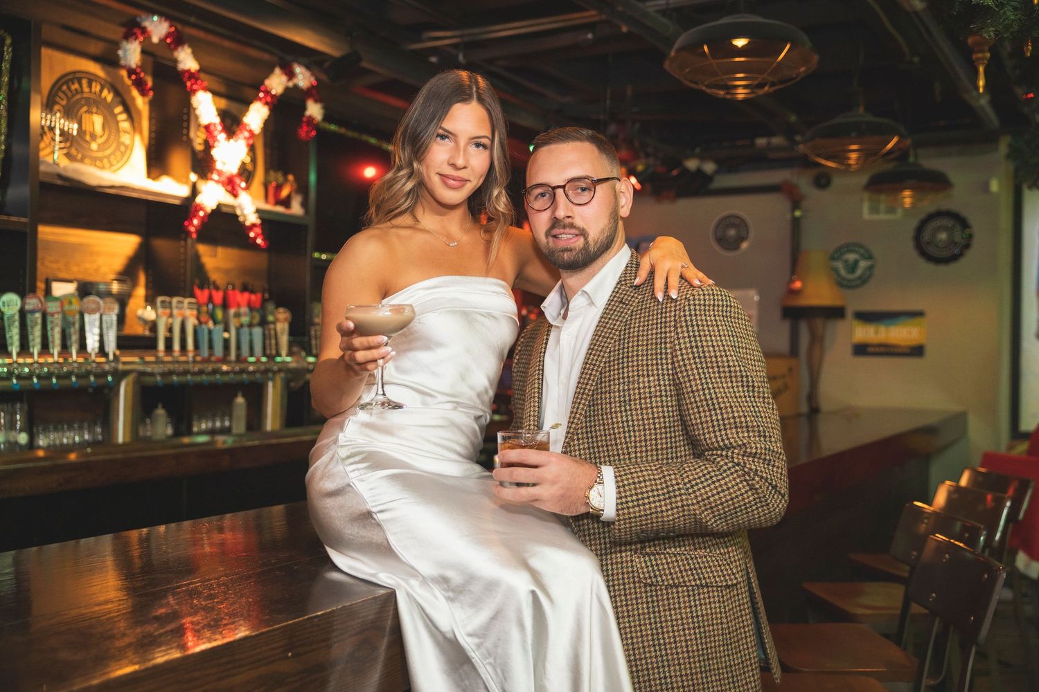 Cozy bar scene with twinkling lights and a couple enjoying drinks together.