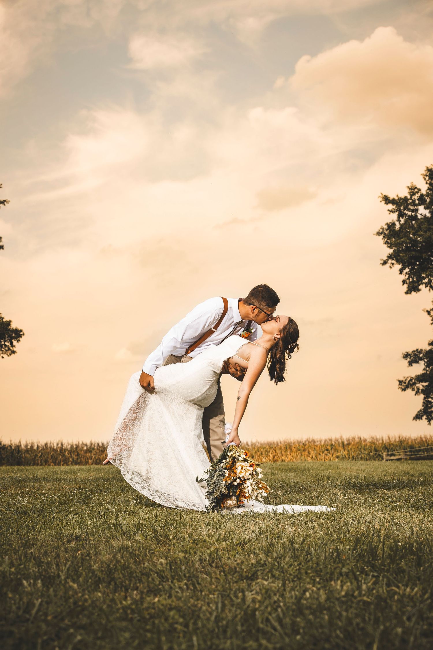 Romantic sunset wedding portraits in grassy field with dramatic dip pose.