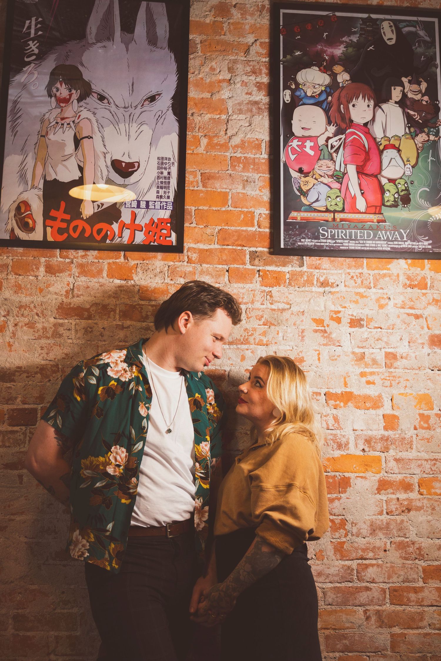 Bar scene with anime posters on exposed brick wall.