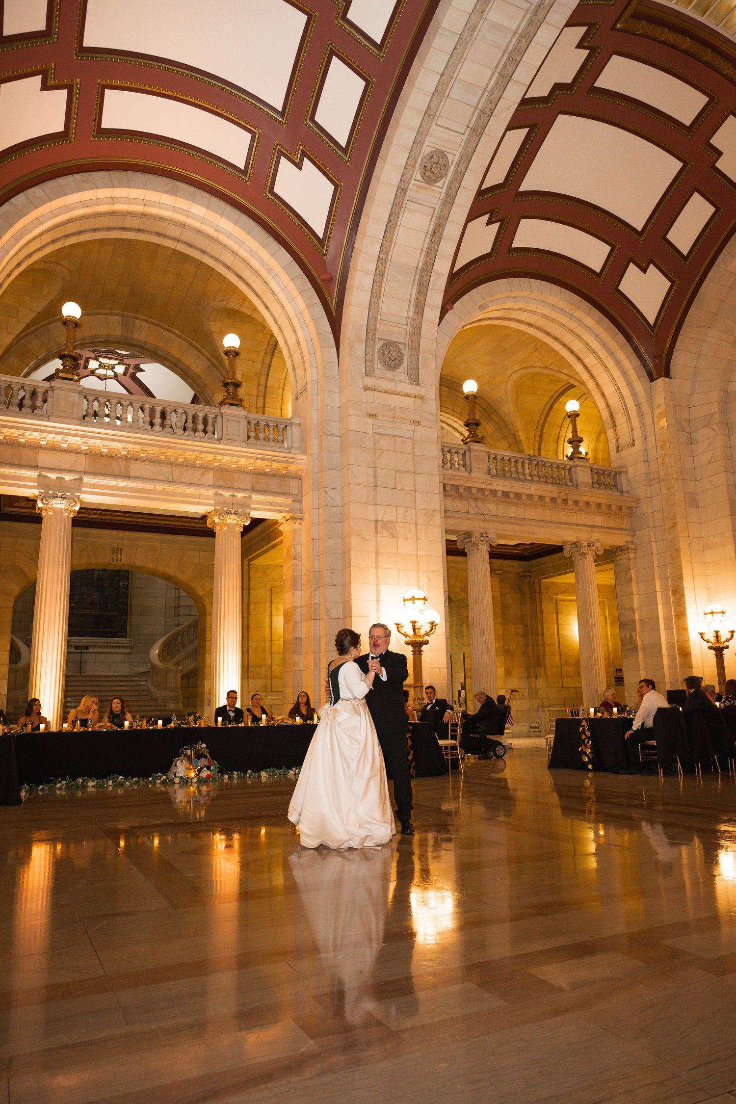 Elegant ballroom with arched ceilings and marble columns illuminated for evening reception.