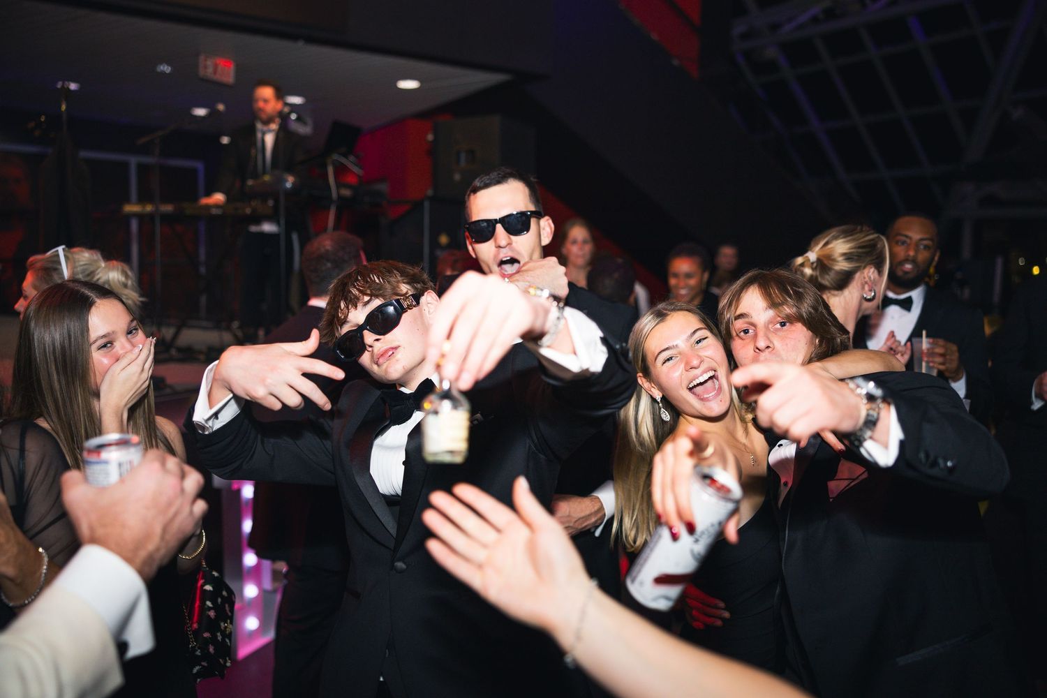 Wedding reception guests dancing and embracing on crowded dance floor.