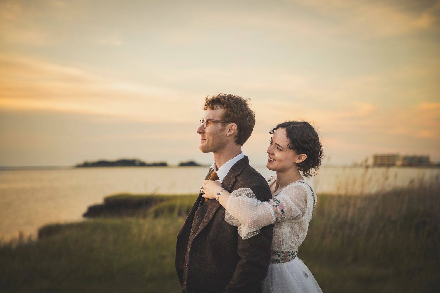 Romantic sunset wedding portrait with warm golden light in coastal setting.