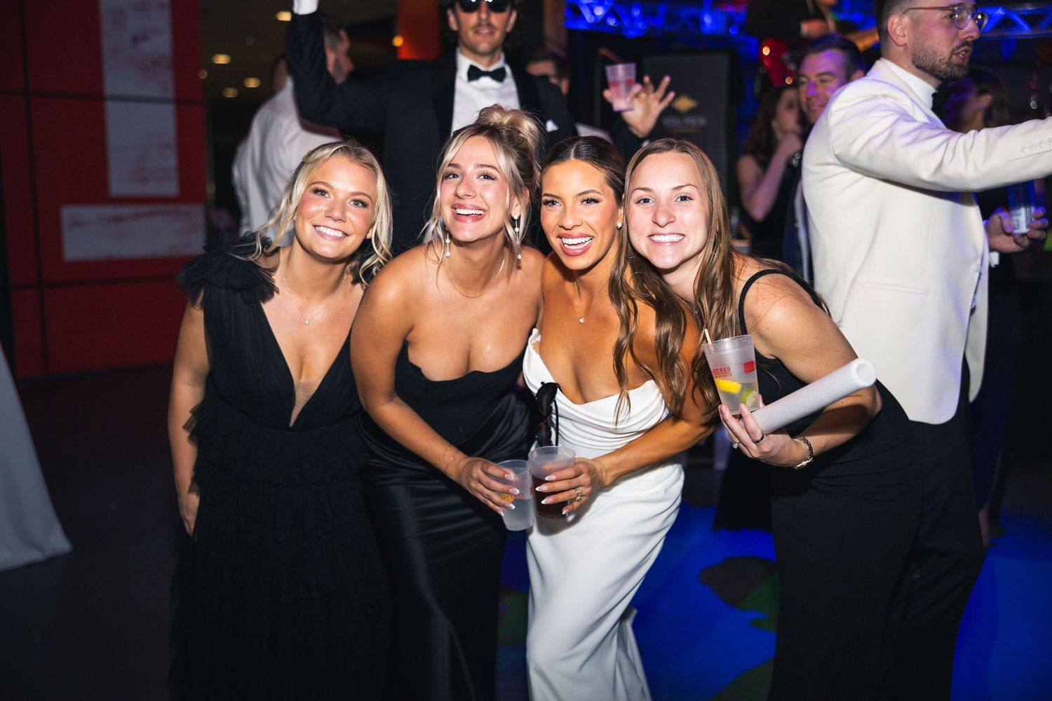 Wedding party group poses together at nighttime celebration venue.
