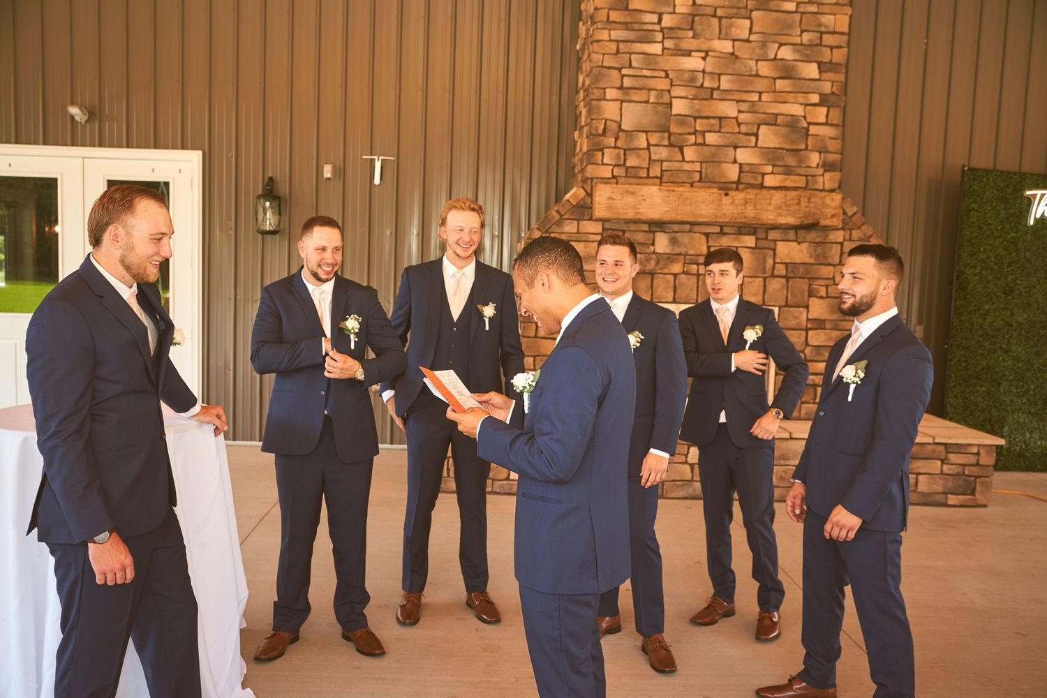 Wedding party in navy suits gathered casually for conversation outside venue.