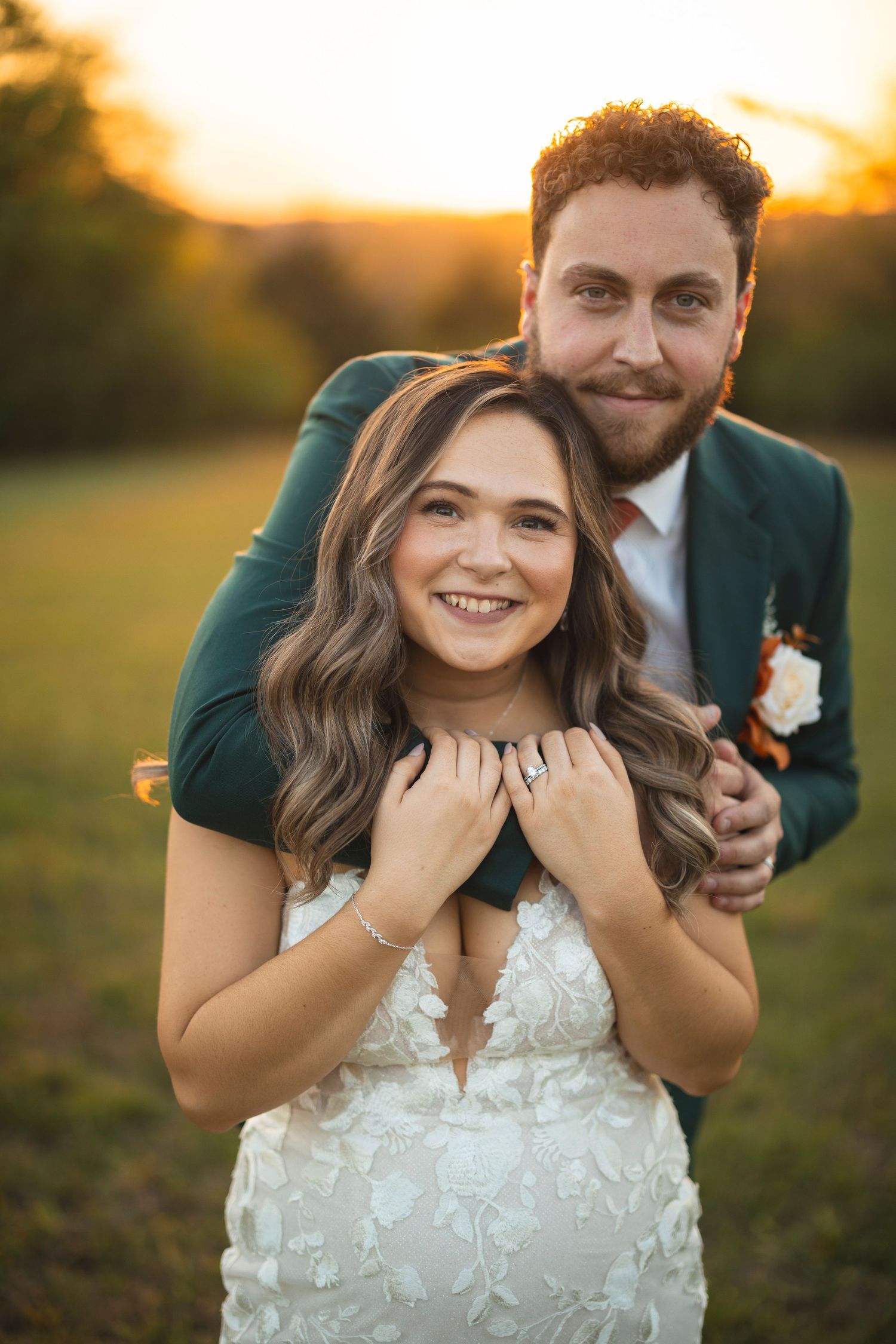 A couple shares a joyful candid moment together in a sunlit field.