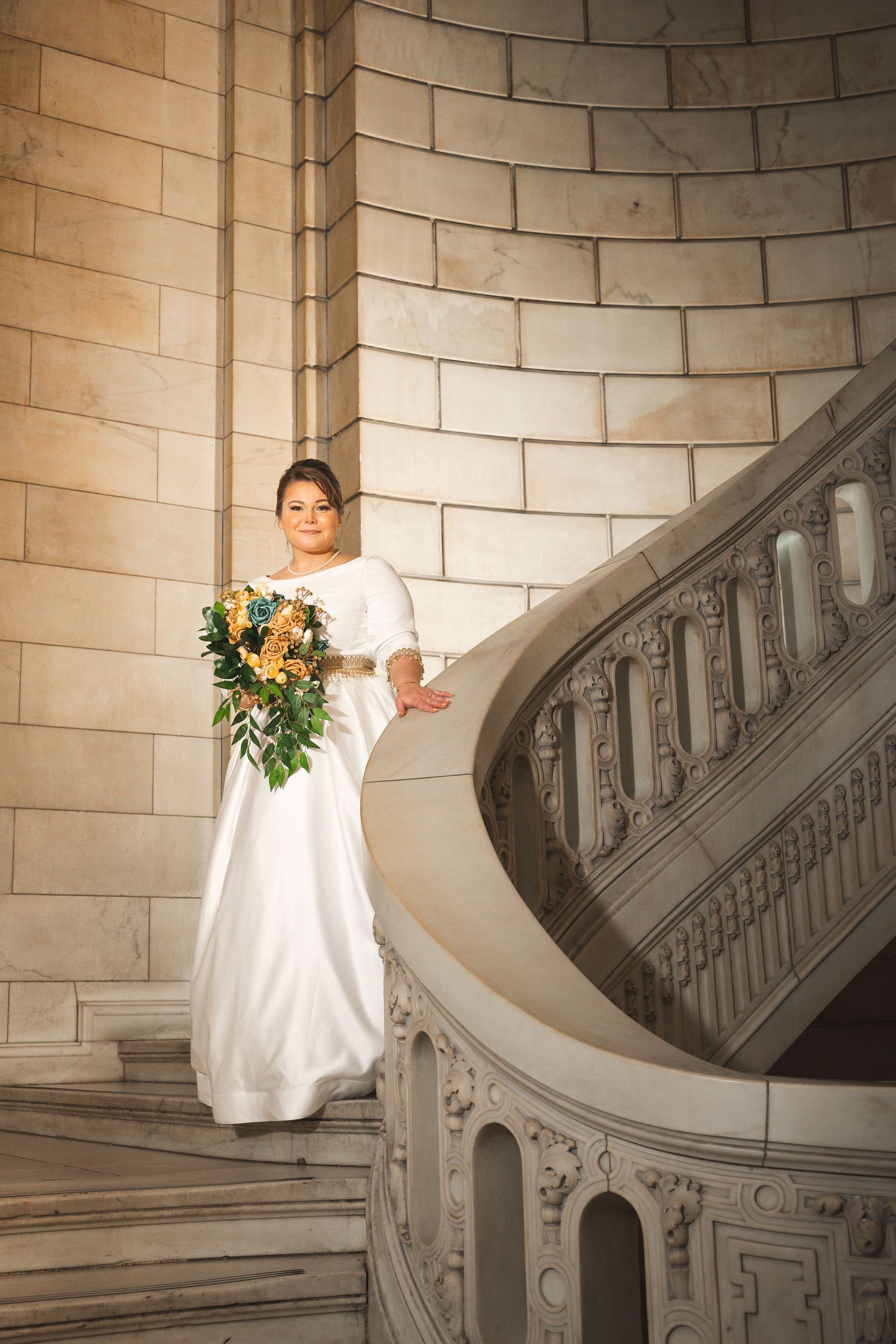 Elegant bridal portrait series on curved stone staircase in historic building.