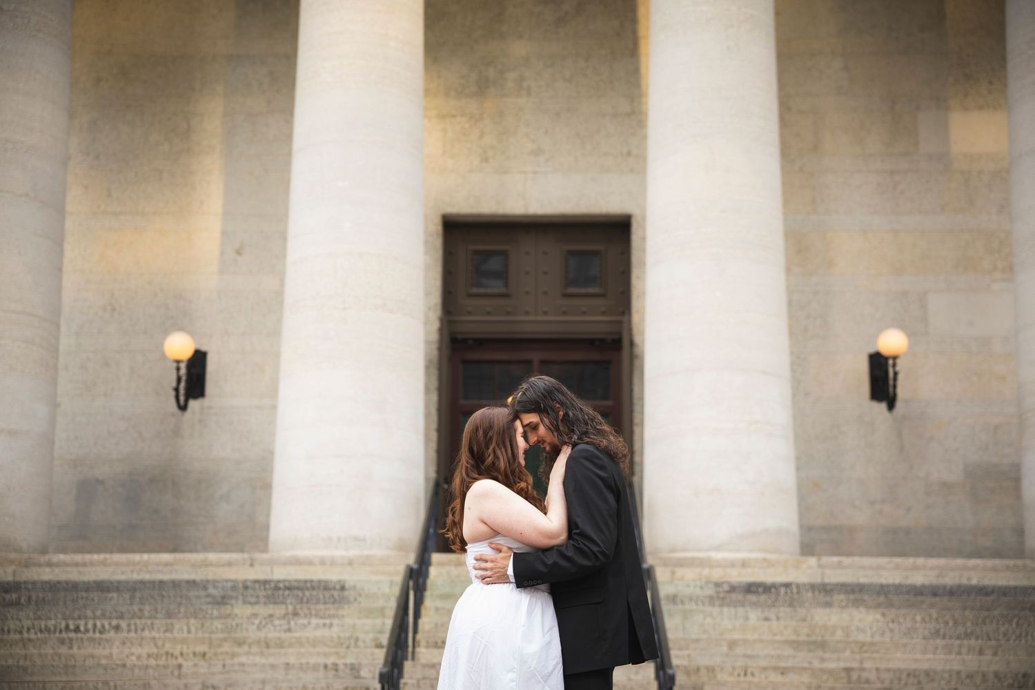 Elegant white columns frame an intimate moment against classic architectural backdrop.