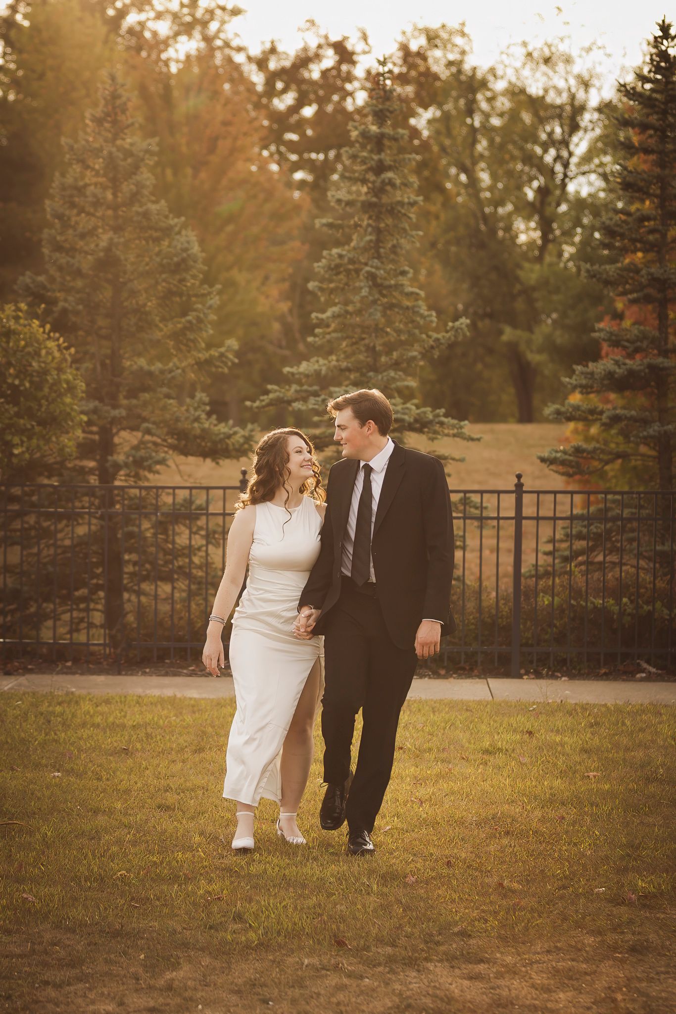 Couple walking together on garden path during autumn sunset.