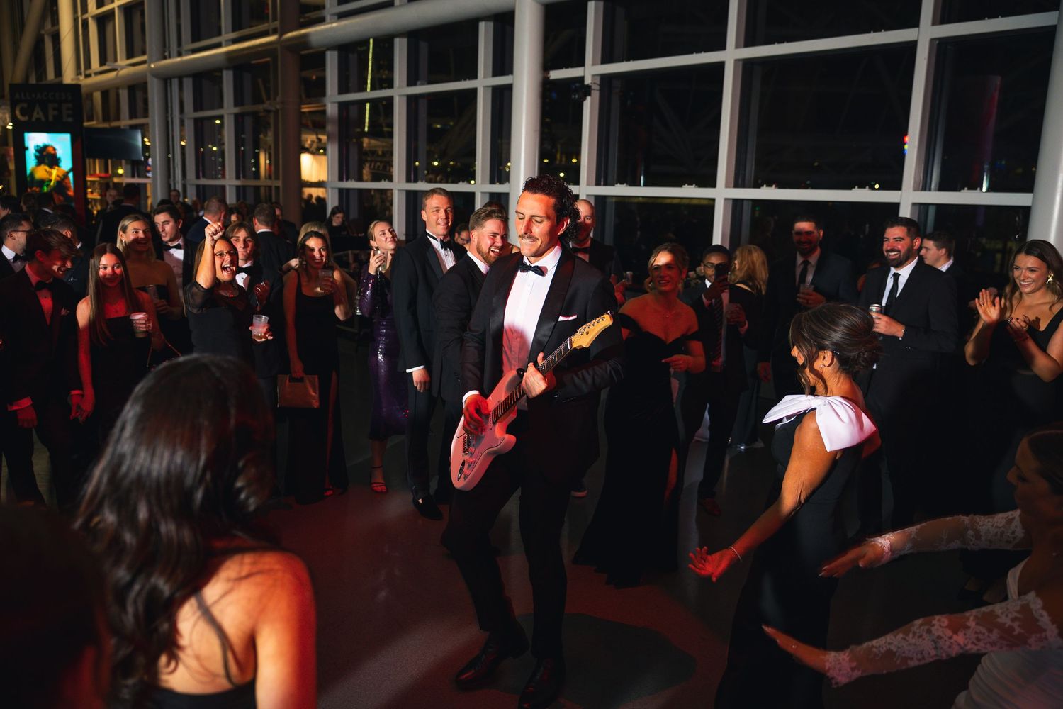 A crowded wedding reception dance floor filled with celebrating guests in formal attire.