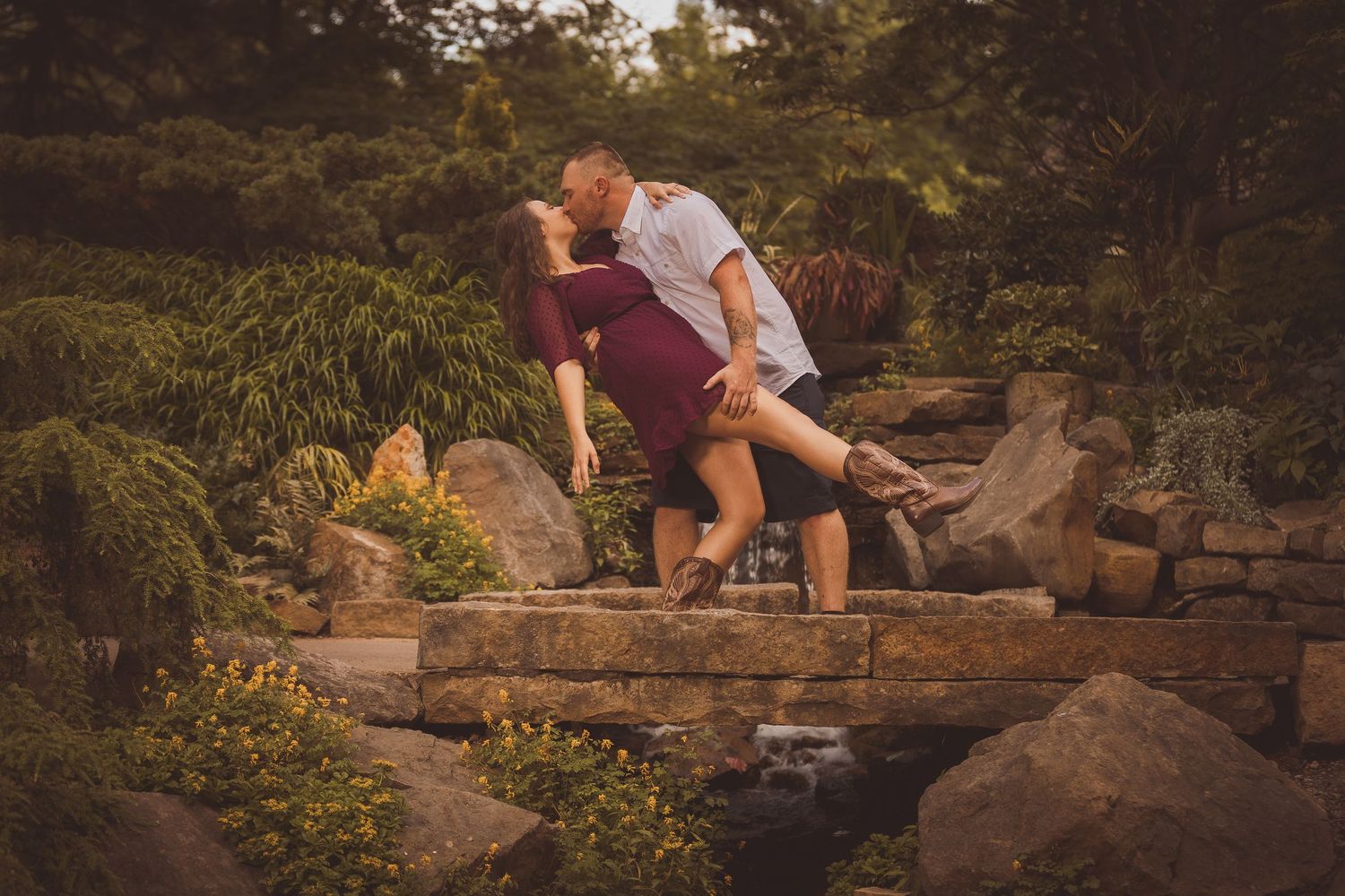 Couple sitting together on large rocks in a natural garden setting.