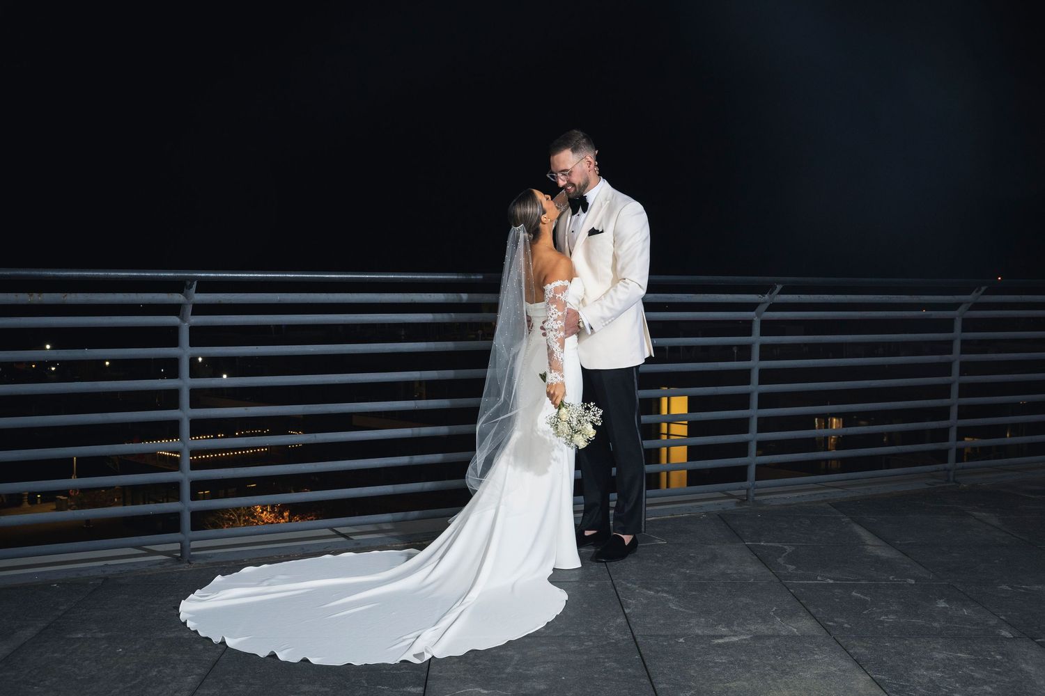 Wedding portrait featuring long train dress against dark industrial backdrop.